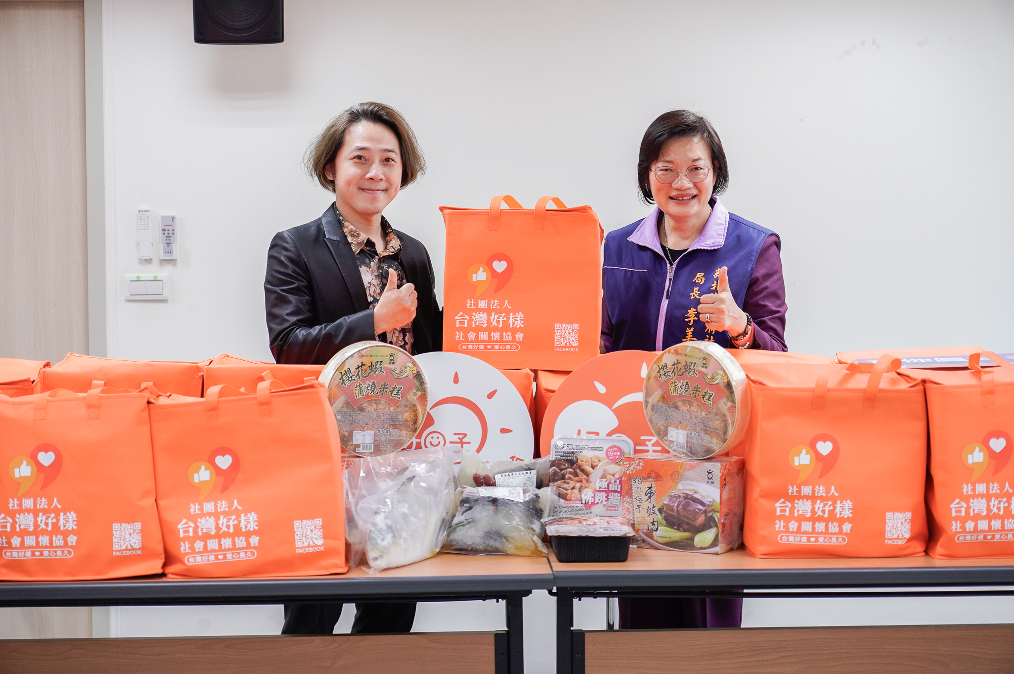 台灣好樣社會關懷協會理事長林建甫(左)與新北市社會局長李美珍(右)合影，年菜內容經協會成員試吃挑選，並以客製化保冷袋包裝，兼顧營養與實用性。
