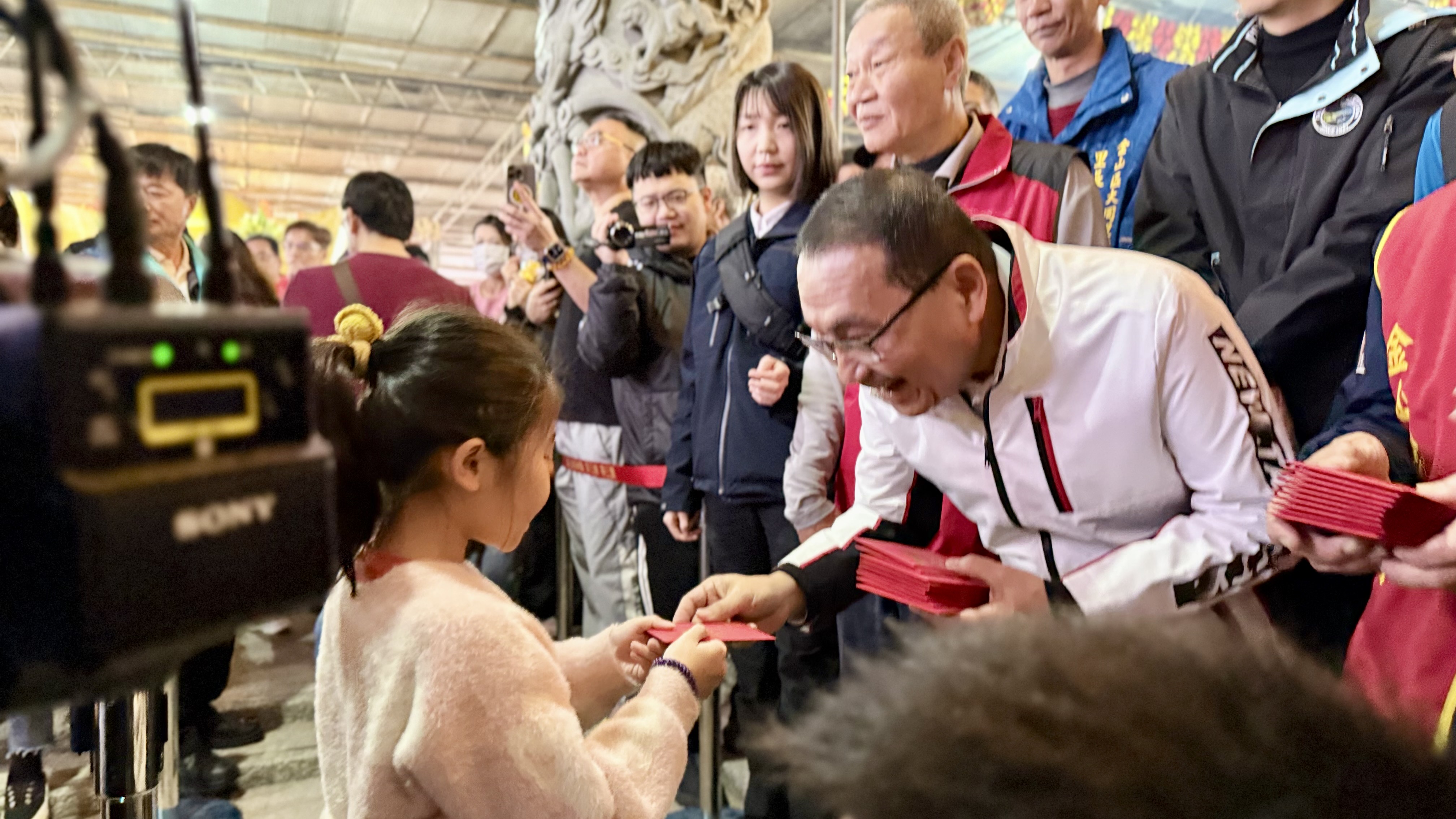 市長侯友宜上午前往金山財神廟，發送「馬上賺錢」福袋，給予小朋友祝福。