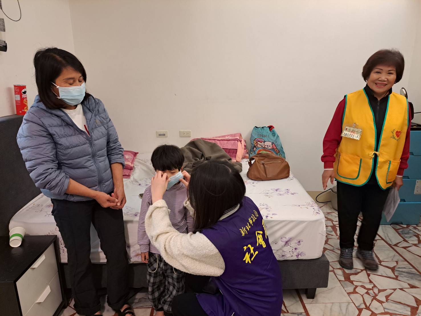 泰五林社福中心主責社工陳語彤細心的將女童的口罩戴好 右1為一竹慈善會前理事長許品