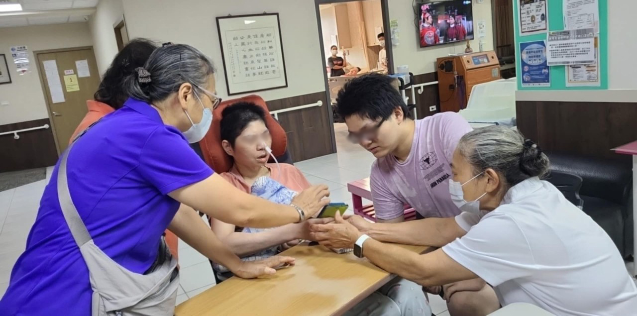  在社工和溫心天使的協助下 阿宏的母親（中）和阿宏（右2）透過手機與在機構的小瑞視訊
