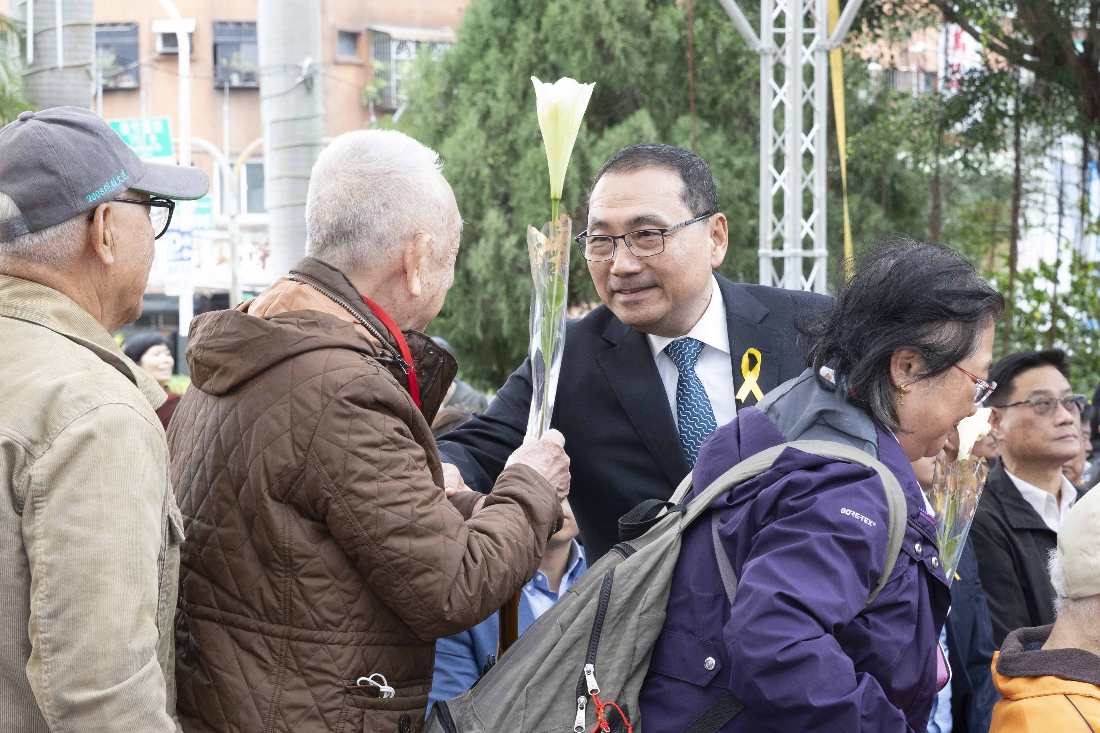 市長逐一遞送鐵炮百合給受難者家屬獻花，撫慰受難者心靈，傳遞和平與希望