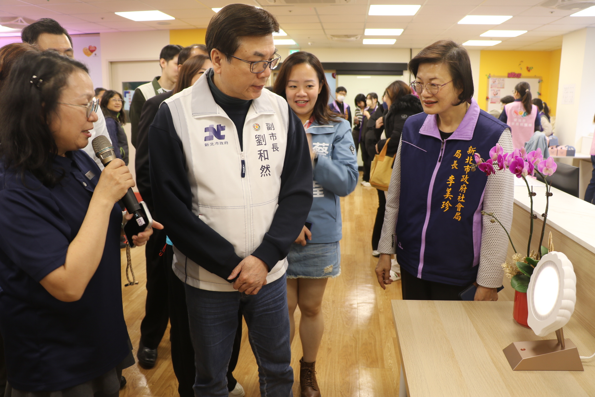 五股成州身障日照中心主任江明芬（左1）為劉和然介紹採用40赫茲（Hz）的貝殼燈，可穩定心智障礙者的情緒