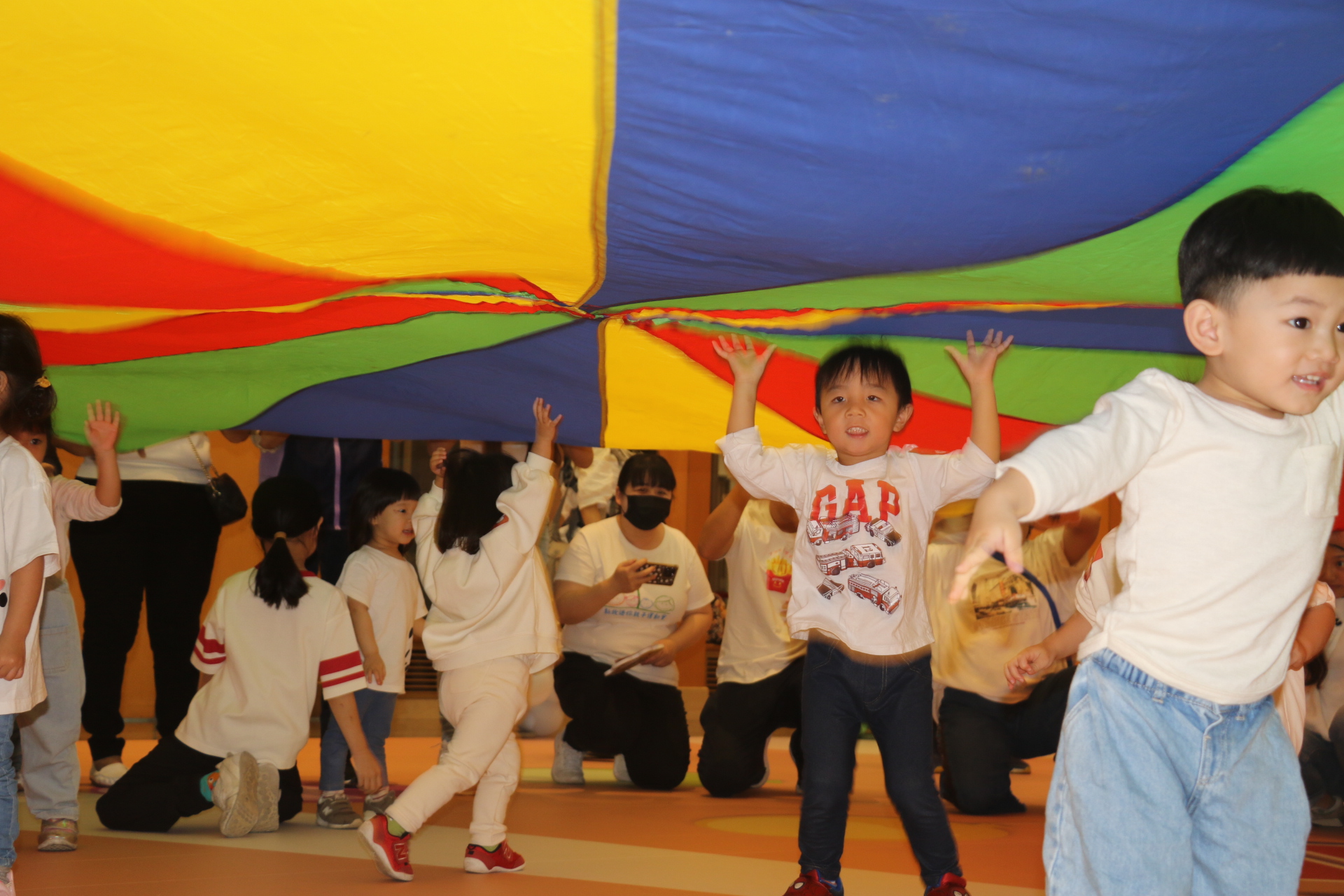  小朋友躲在氣球傘下玩
