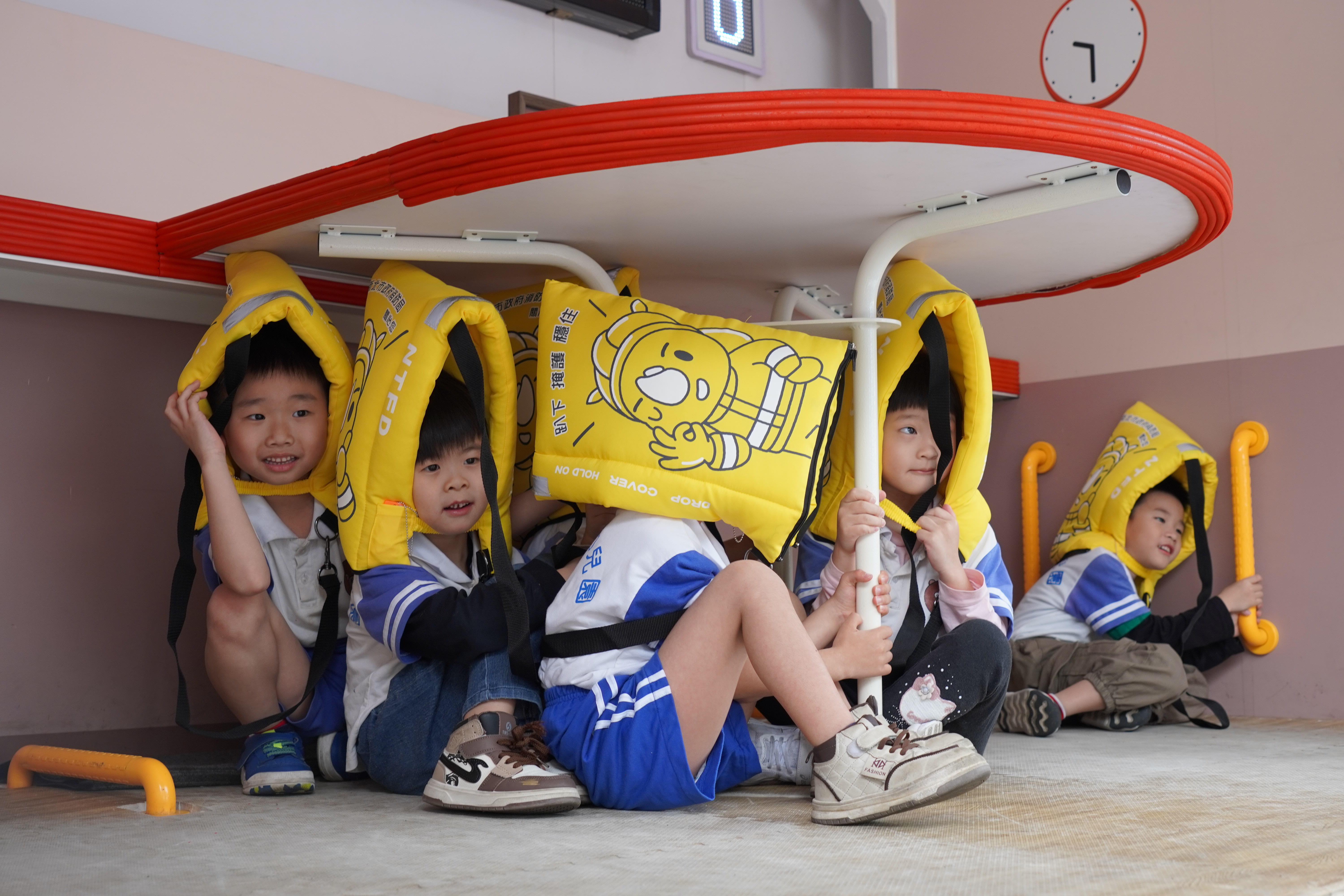 小朋友在地震體驗車內戴保護頭套 躲在桌下.