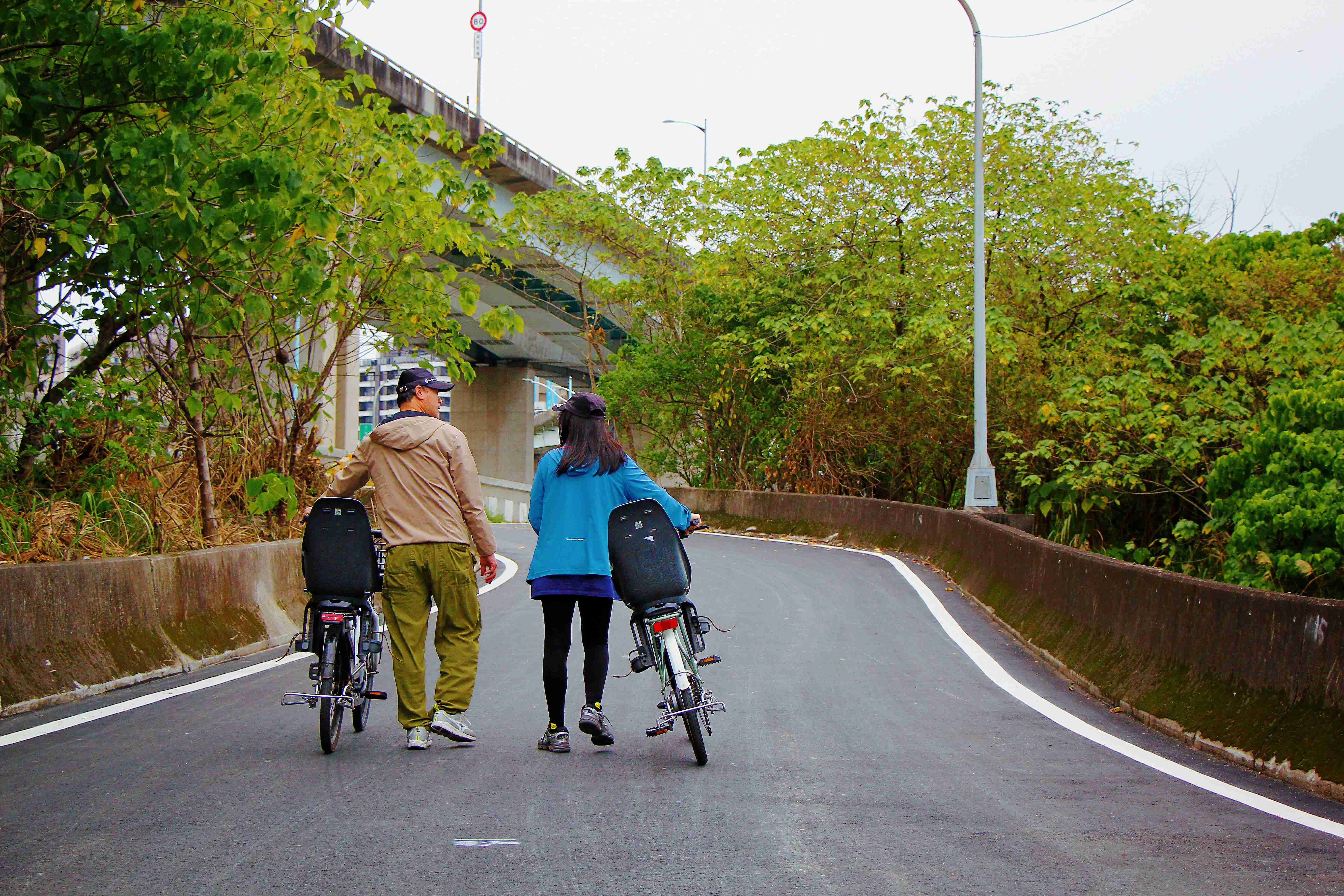  伴隨悠閒談笑聲，牽車步行於蜿蜒小徑