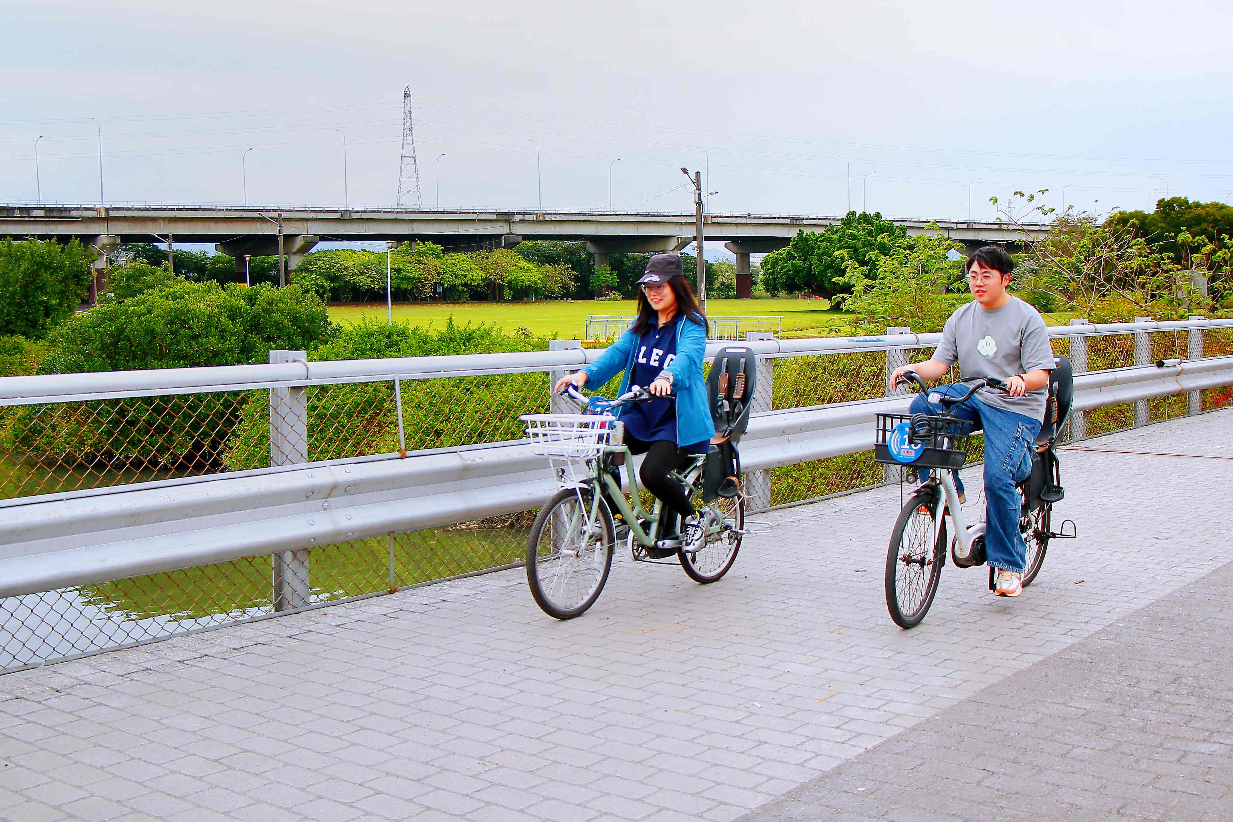  兩人並肩騎行，展開悠閒的河濱單車之旅