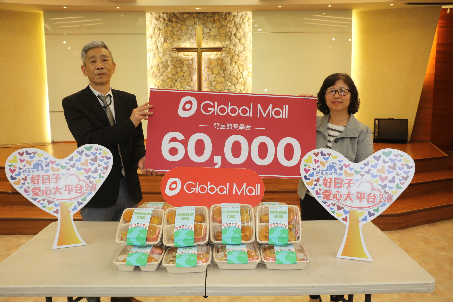  環球購物中心副總經理翁德建（左）捐贈6萬元商品券 及300份兒童餐 合計12萬元 由社會局副局長許秀能代表受贈