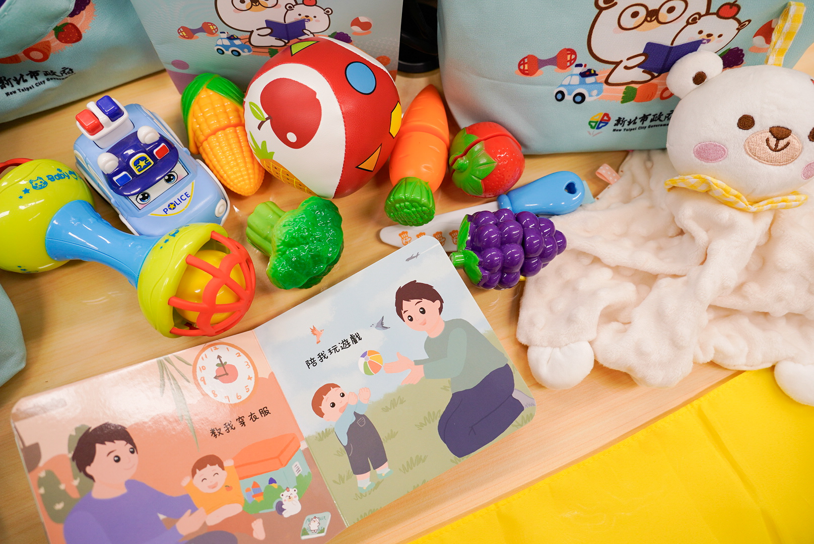  育兒寶貝袋內有安撫巾、手搖鈴、迴力車和寶寶一天作息繪本等