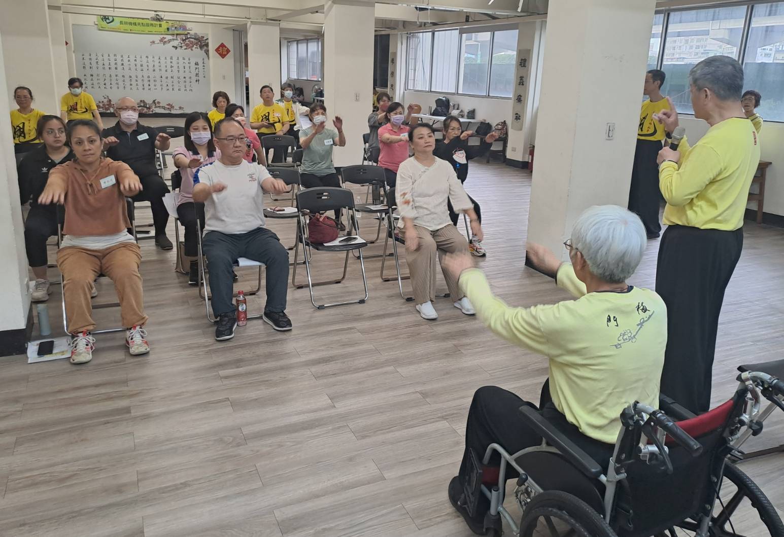  梅門師兄李志恆（右1）培訓長照機構負責人 示範教導如何讓坐輪椅者也可以運用上肢平甩 以改善身心健康