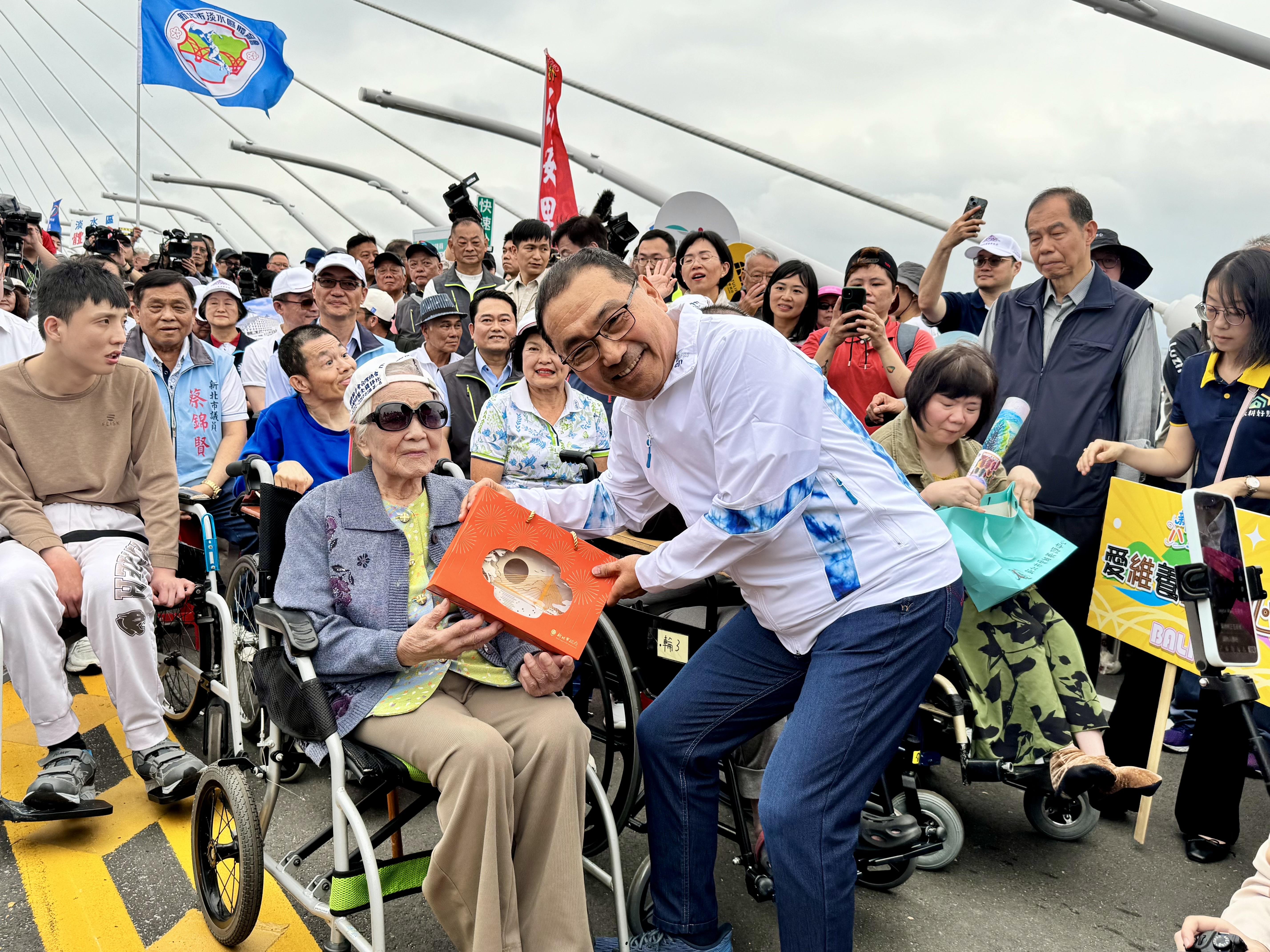 侯友宜向兩位阿嬤致意，並致贈淡江大橋意象燈飾祝福。