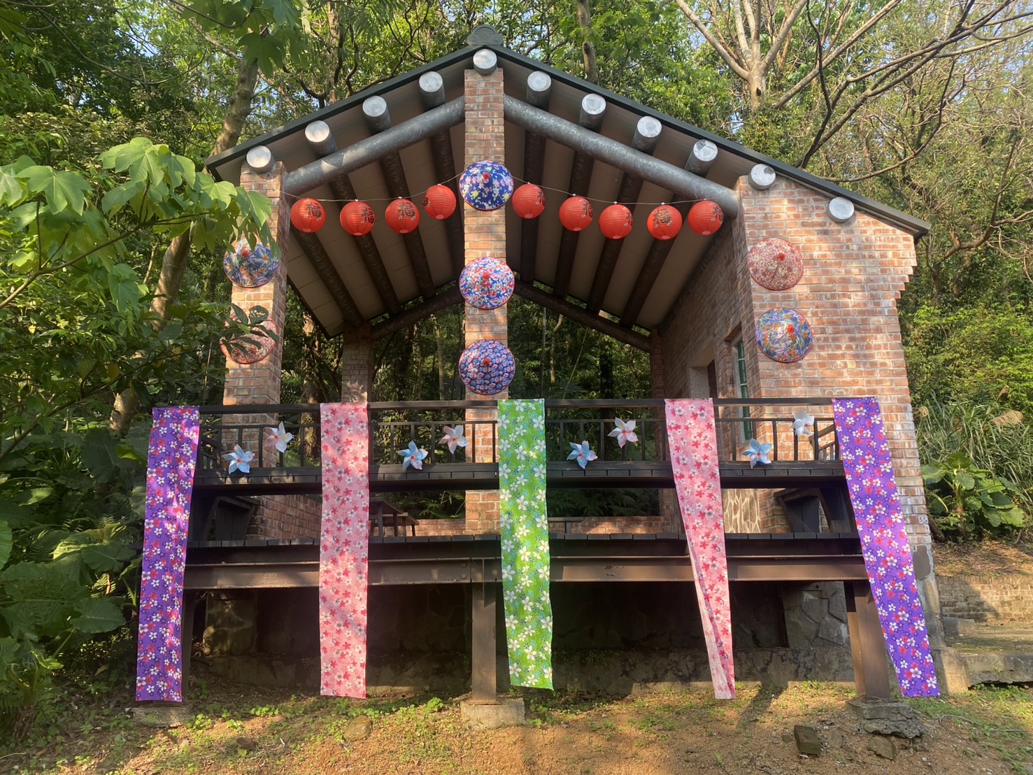 三芝客家奉茶亭裝飾著繽紛的客家花布燈籠與斗笠，在桐花盛開季節時供遊客停駐休息並感受濃厚客家風情