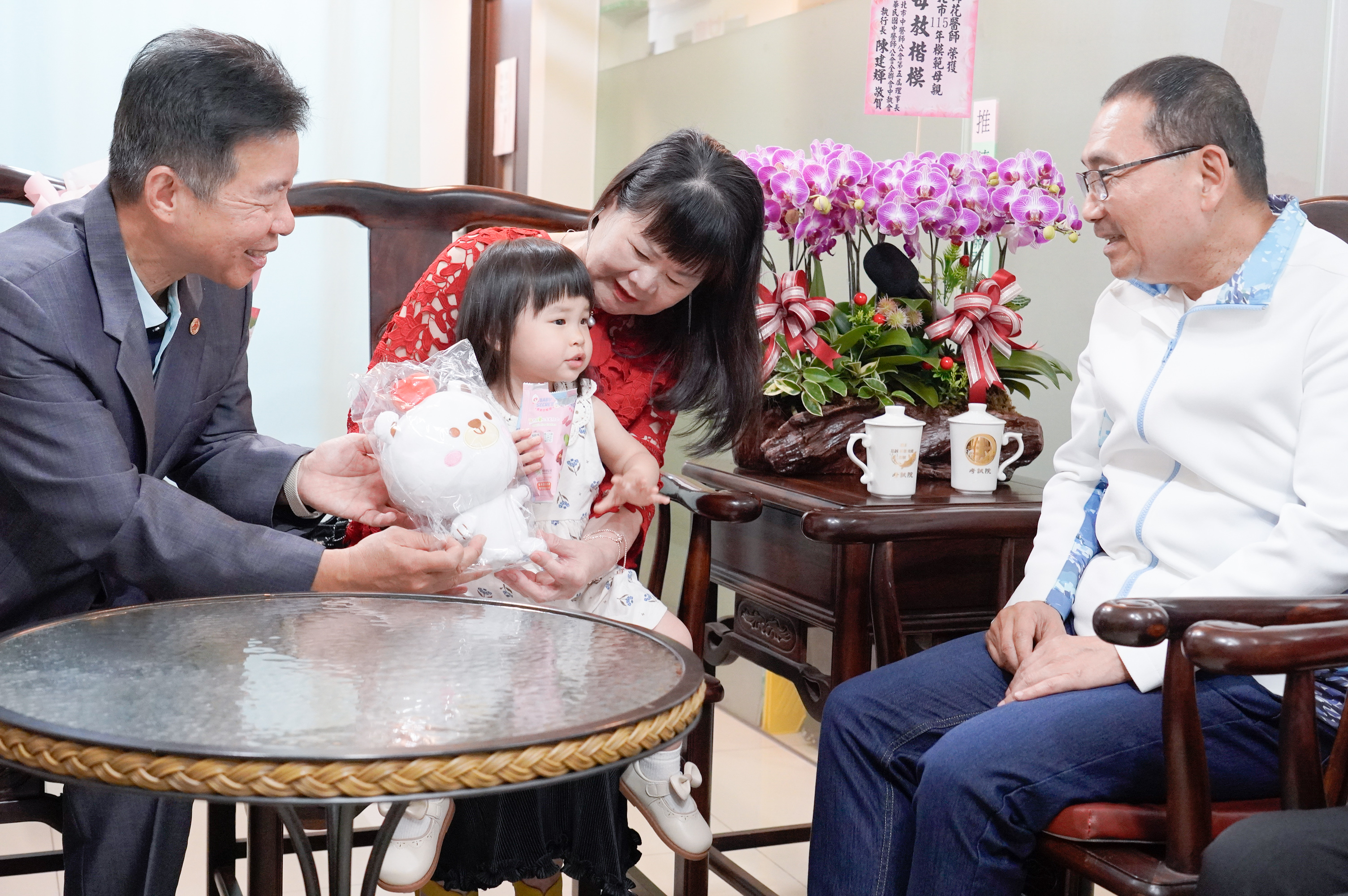 康錦花與孫女感情融洽，侯友宜特地致贈「熊果」玩偶，祝她平安尚大漢。 左1為同是中醫師的先生洪啟超。