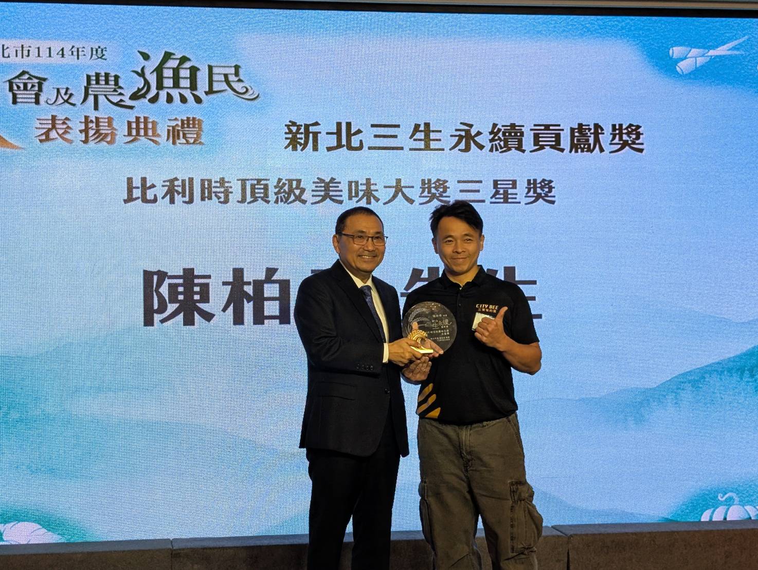 青農陳柏承(右)生產蜂蜜並轉化為具附加價值產品，榮獲「比利時頂級美味大獎三星獎」榮耀，市長侯友宜頒發「新北三生永續貢獻獎」表揚青農陳柏承的創新實力