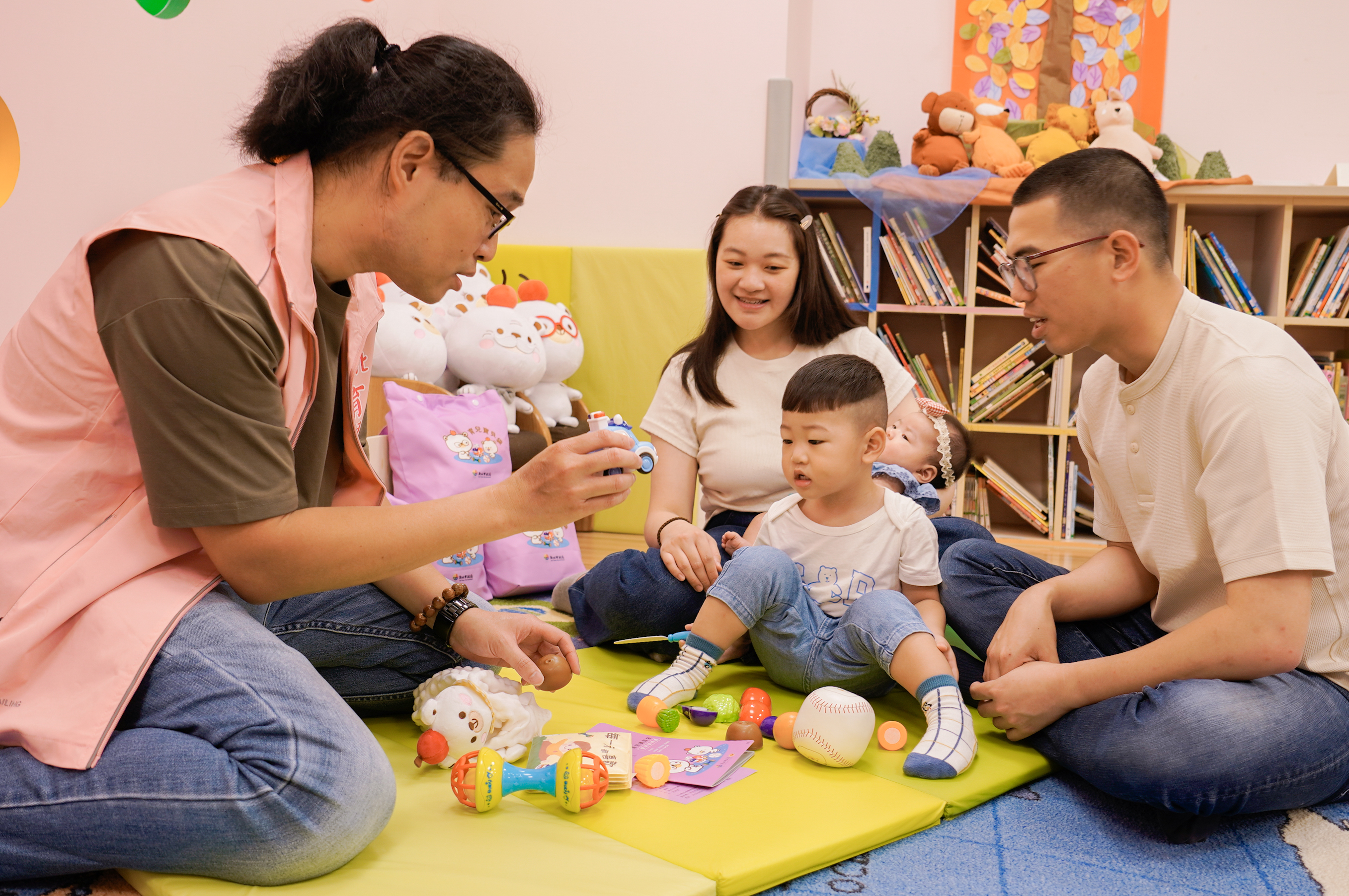  新北市設置幼兒指導員（左1），可以協助新生兒父母育兒指導，利用寶貝袋裡面的內容物來跟孩子進行發展篩檢。