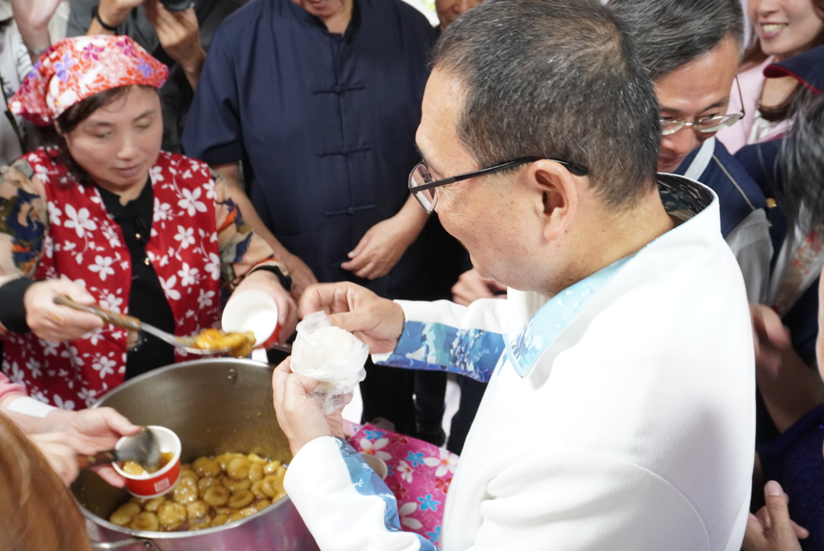 侯友宜市長在活動現場的美食區與鄉親話家常，並品嚐客家菜包，氣氛熱鬧、溫馨。