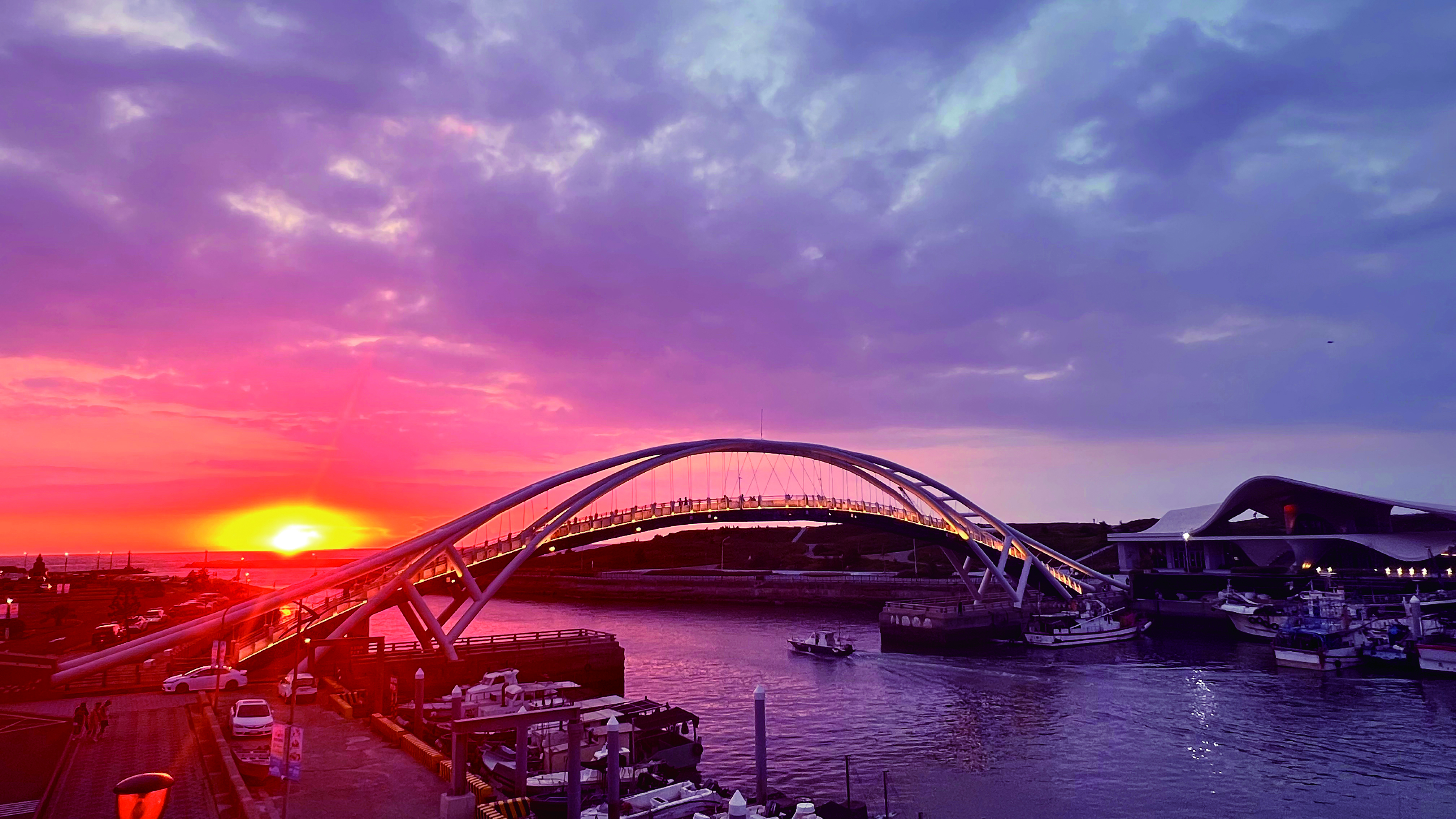 桃園竹圍漁港夕陽餘暉灑落海面，漁港天橋與港灣景致交織出浪漫迷人風光。