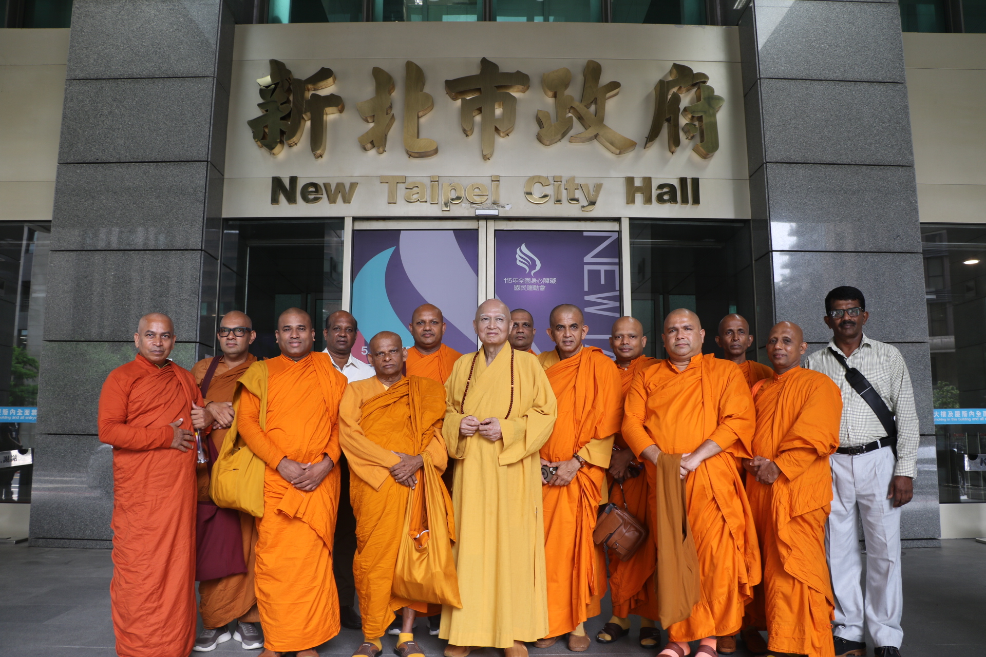  斯里蘭卡佛教阿瑪拉普拉教派僧團12位長老於心北市府銜牌下留影，中為三峽普賢寺開山住持釋宗道法師。