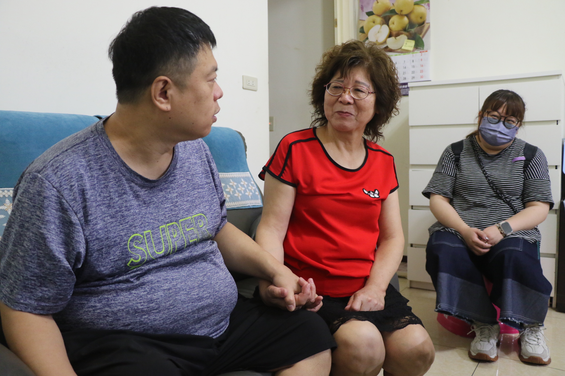  小許握著媽媽的手 母子對視 小許有說不出口的感恩 媽媽也有說不出口的無奈 右1為新北市樂慧服務中心的社工尤詩菱