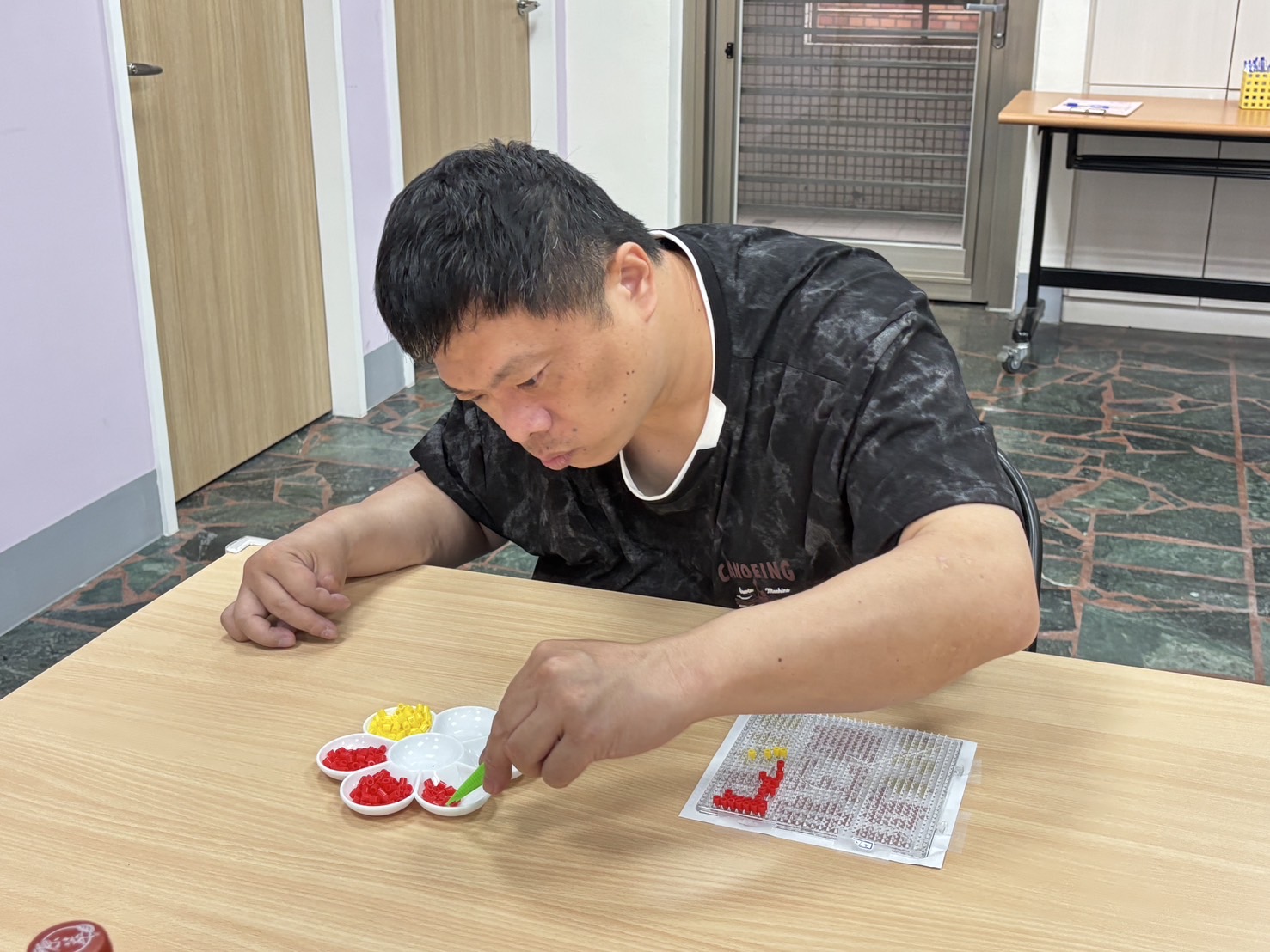  小許在樂慧中心參加「藝起動手做」，認真地拼出豆豆世界。