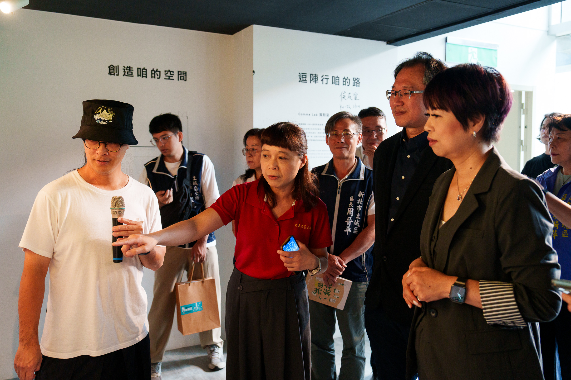 由新北市景觀總顧問為參與貴賓導覽《共築新北》微型展，聽取計畫團隊說明新北城鄉風貌及社區規劃案例。