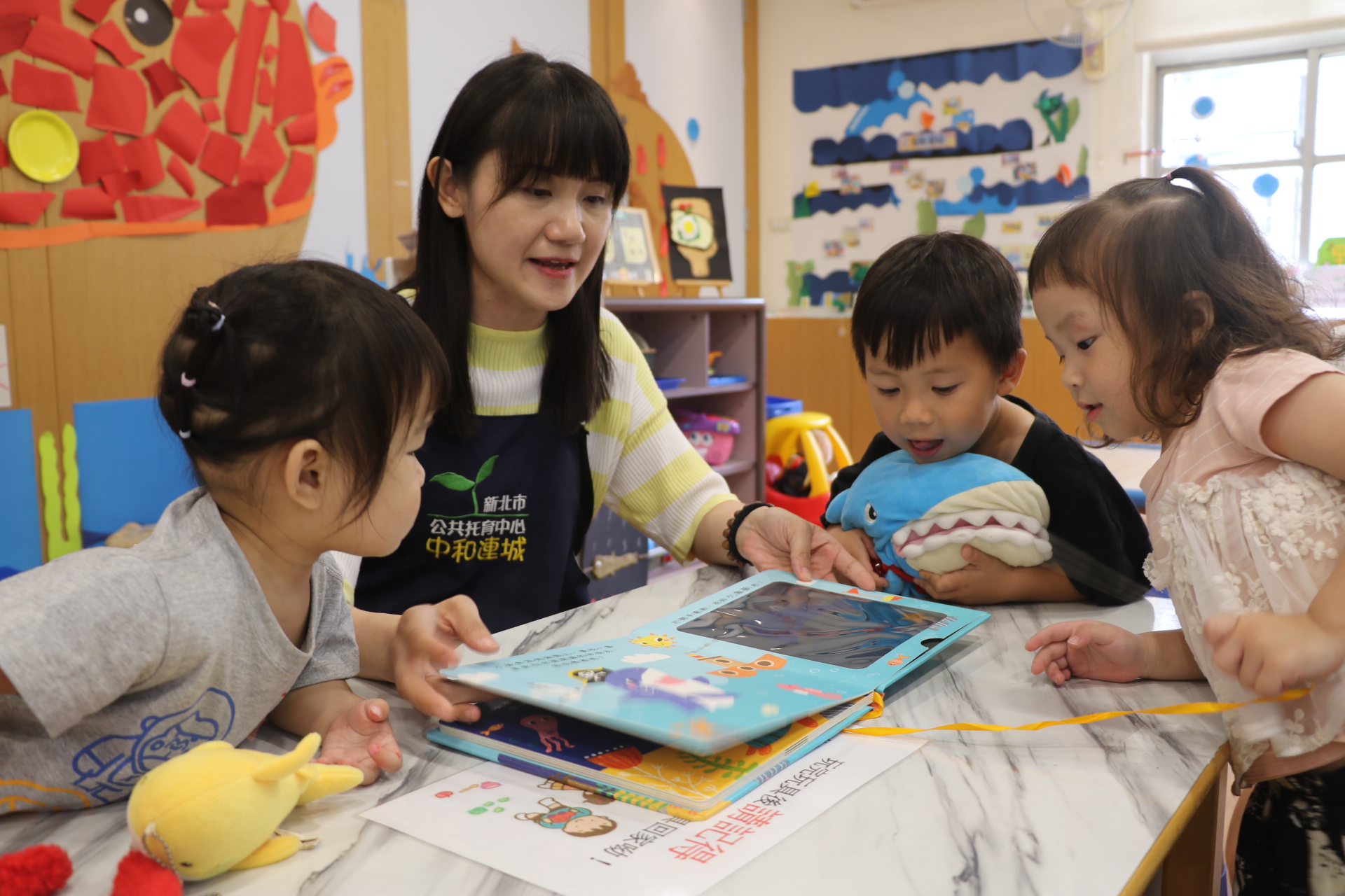  中和連城公托親子館黃品珍老師利用繪本為幼兒解說海底世界的生物 吸引小朋友觀賞