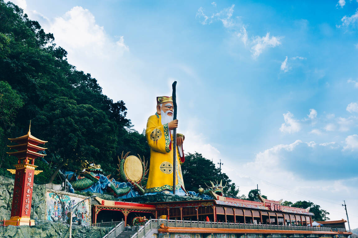  遠眺中和烘爐地地標。手持拐杖與金元寶的巨大土地公像，是山林間最莊嚴亮眼的身影。