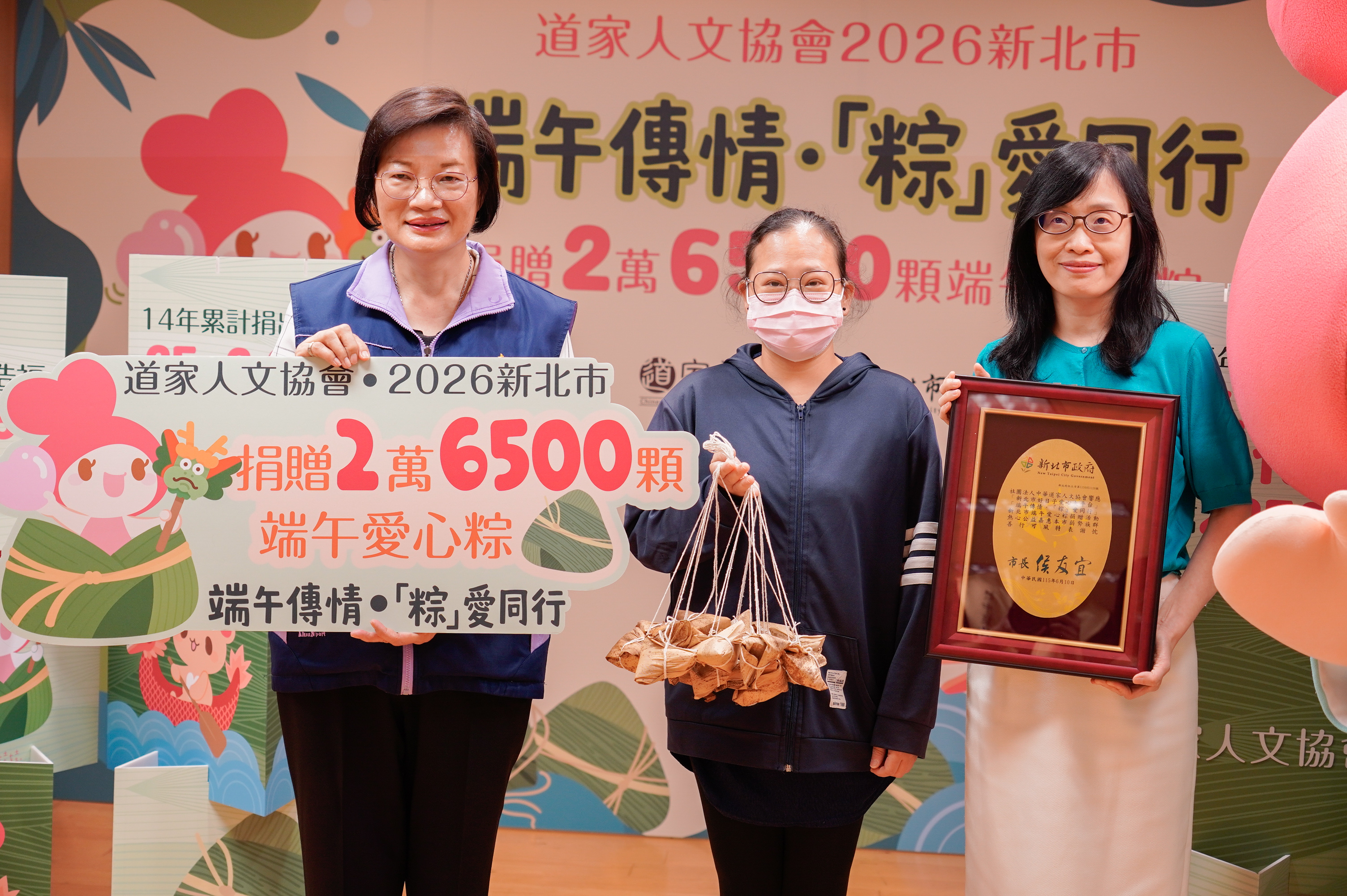 社會局長李美珍(左)代表侯友宜市長致贈感謝牌，與中華道家人文協會將粽子給予受贈代表小真(中)。