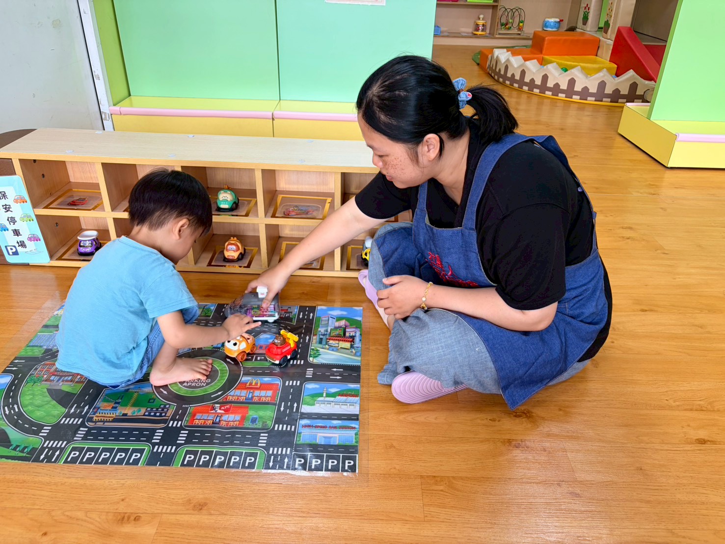  樹林保安公托中心親子館定點臨托的托育人員陪幼兒一起玩汽車