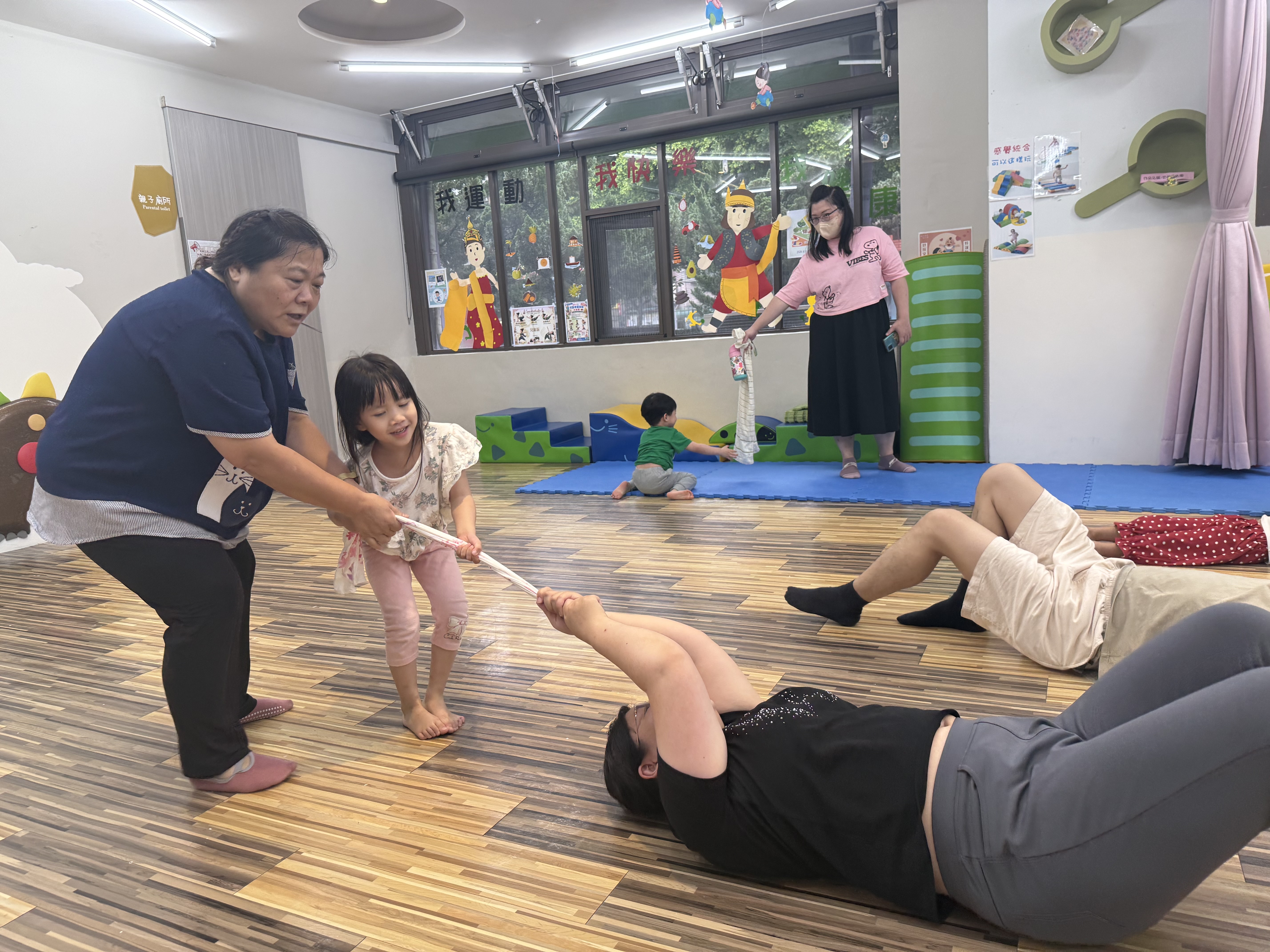  新北市第3區早資中心辦理親子感統團體遊戲，有豐富學前特殊教育經的輔導教師戈良惠（左1）帶領親子遊戲，讓小朋友用毛巾拉著媽媽，非常有趣，也拉近親子關係。