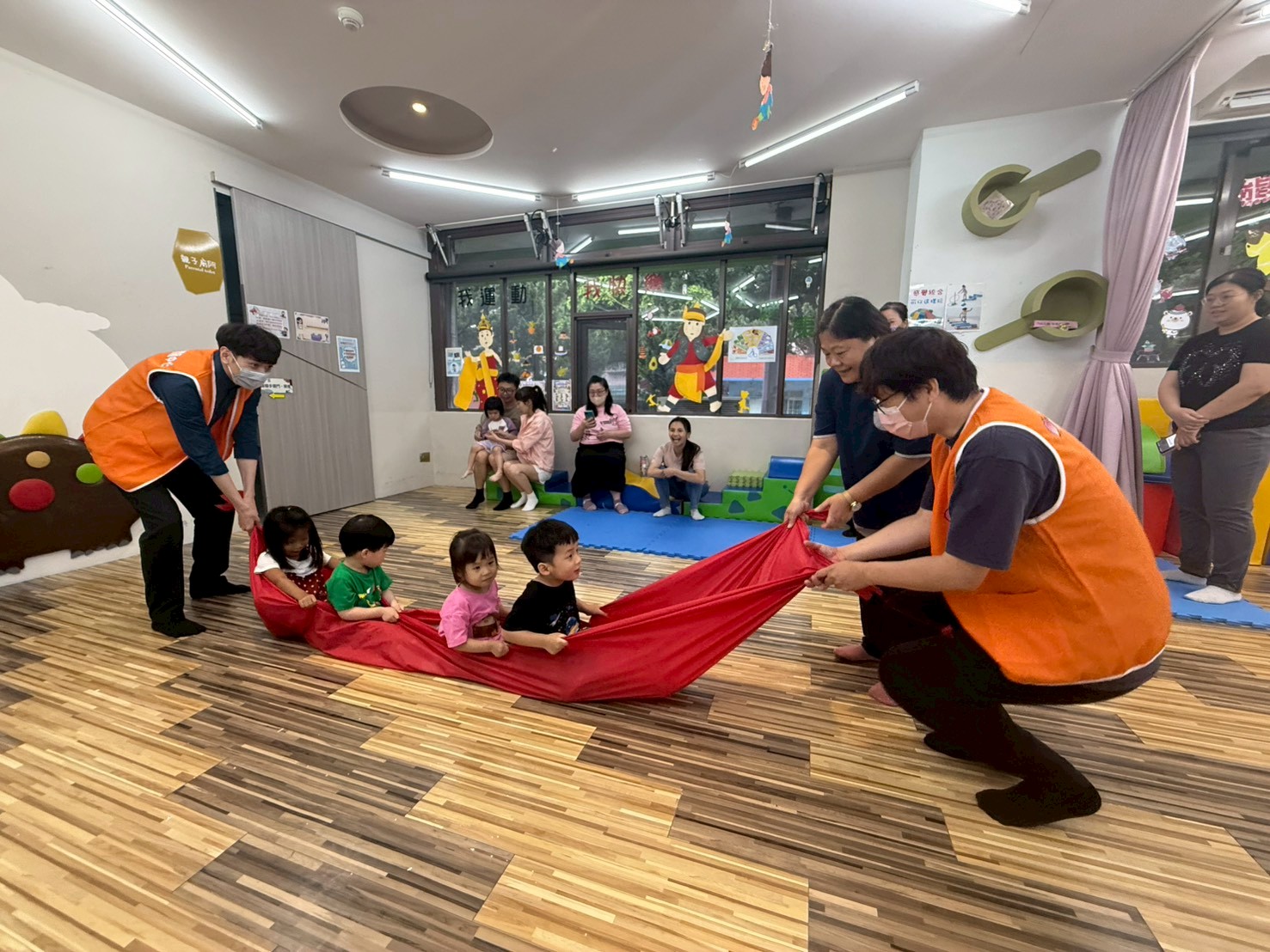 新北市第3區早資中心辦理親子感統團體遊戲，戈良惠老師（右2）帶領小友陸上划龍舟。