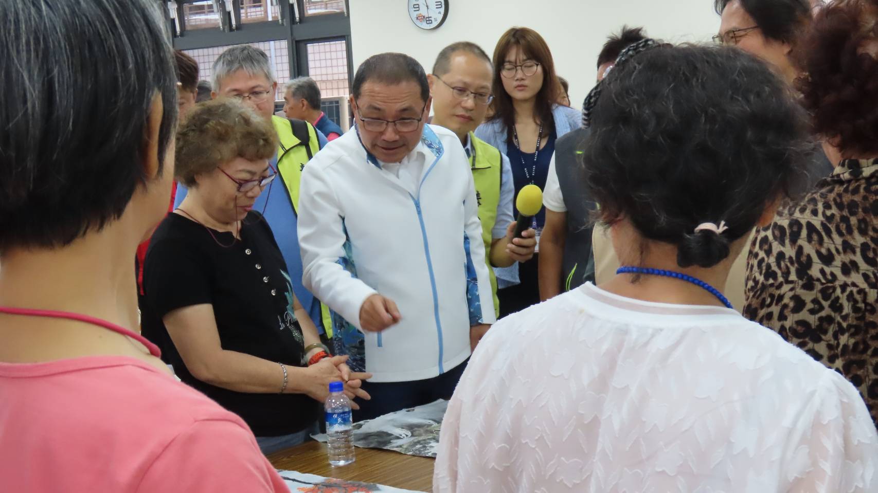 市長侯友宜前往活動中心內的繪畫課程，與學員們互動熱絡合影，留下日出畫作。