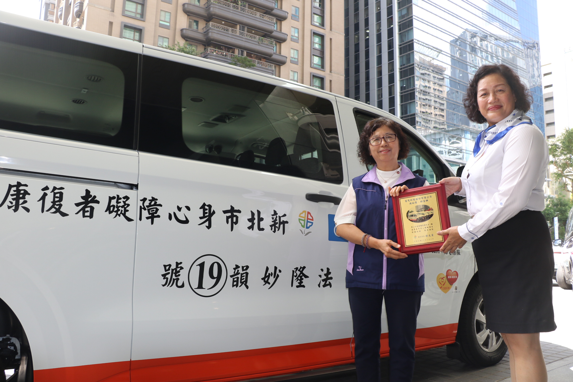  施先生委由車商呂經理捐贈第19輛復康巴士，社會局副局長許秀能（左）代表侯友宜市長回贈感謝牌。