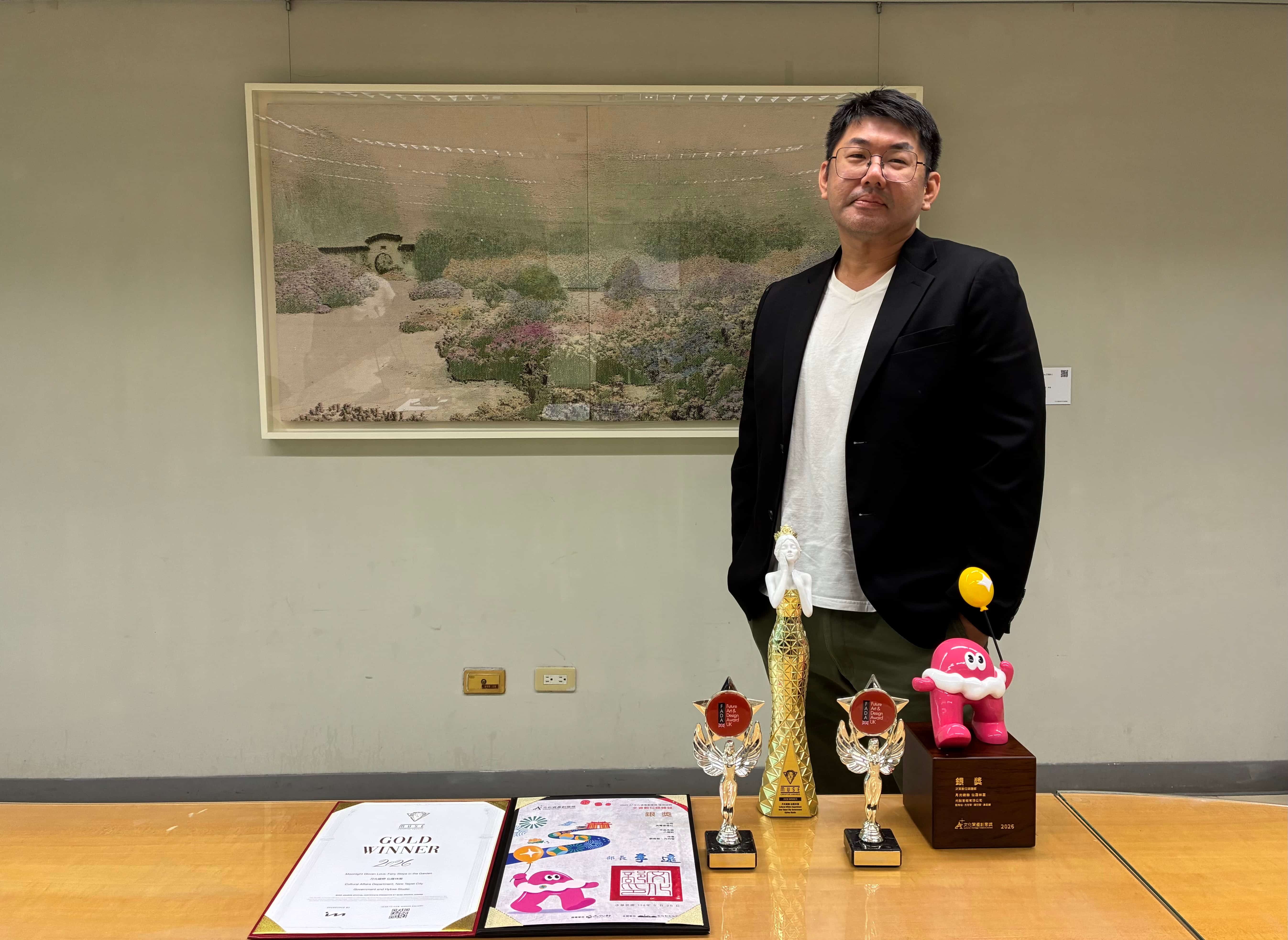 導演劉育樹與《月光織戀 仙履林園》光雕秀獲獎獎盃合影。