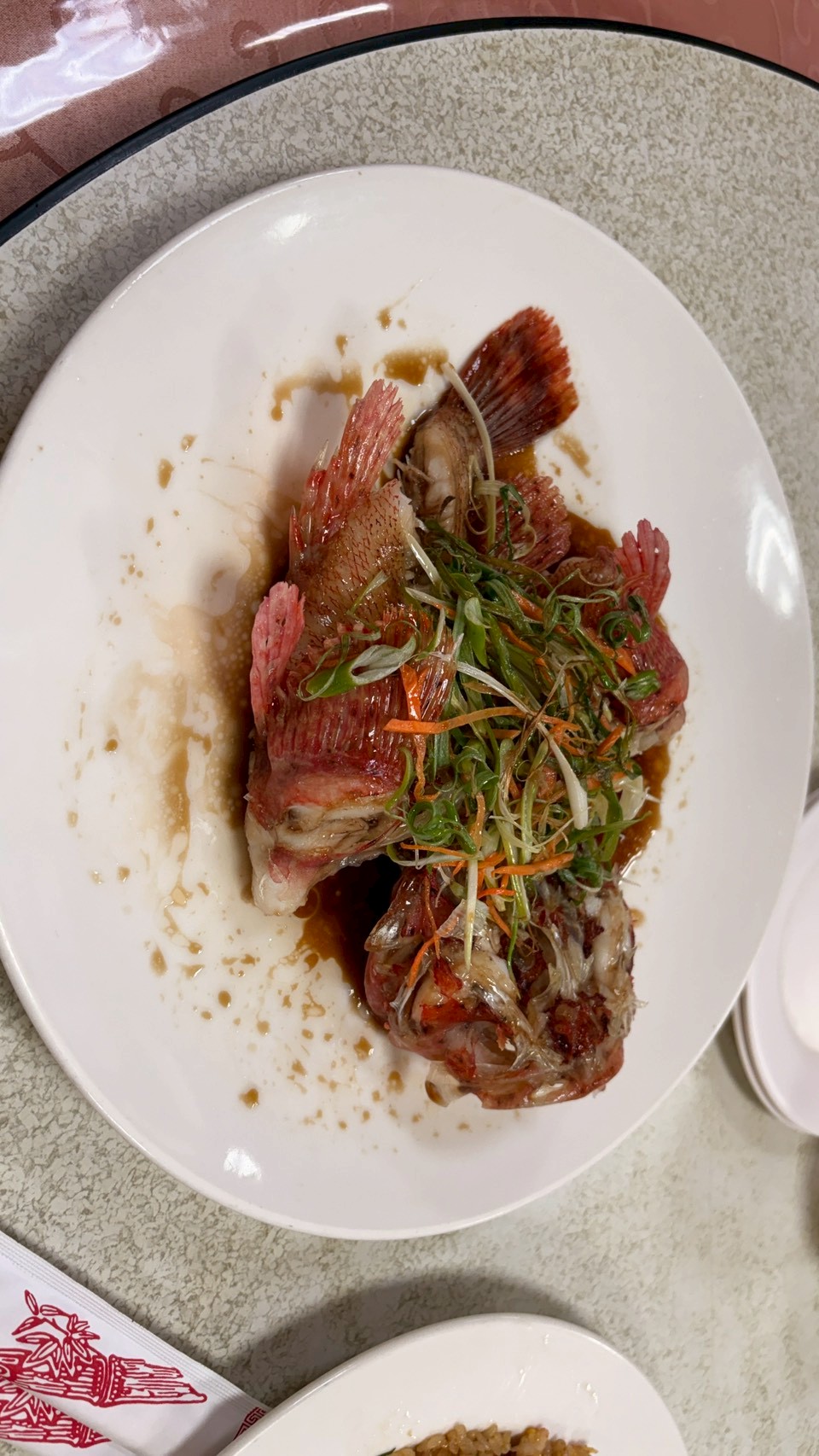 清蒸石狗公搭配蔥絲、薑絲及醬汁，完整呈現魚肉的鮮嫩滋味