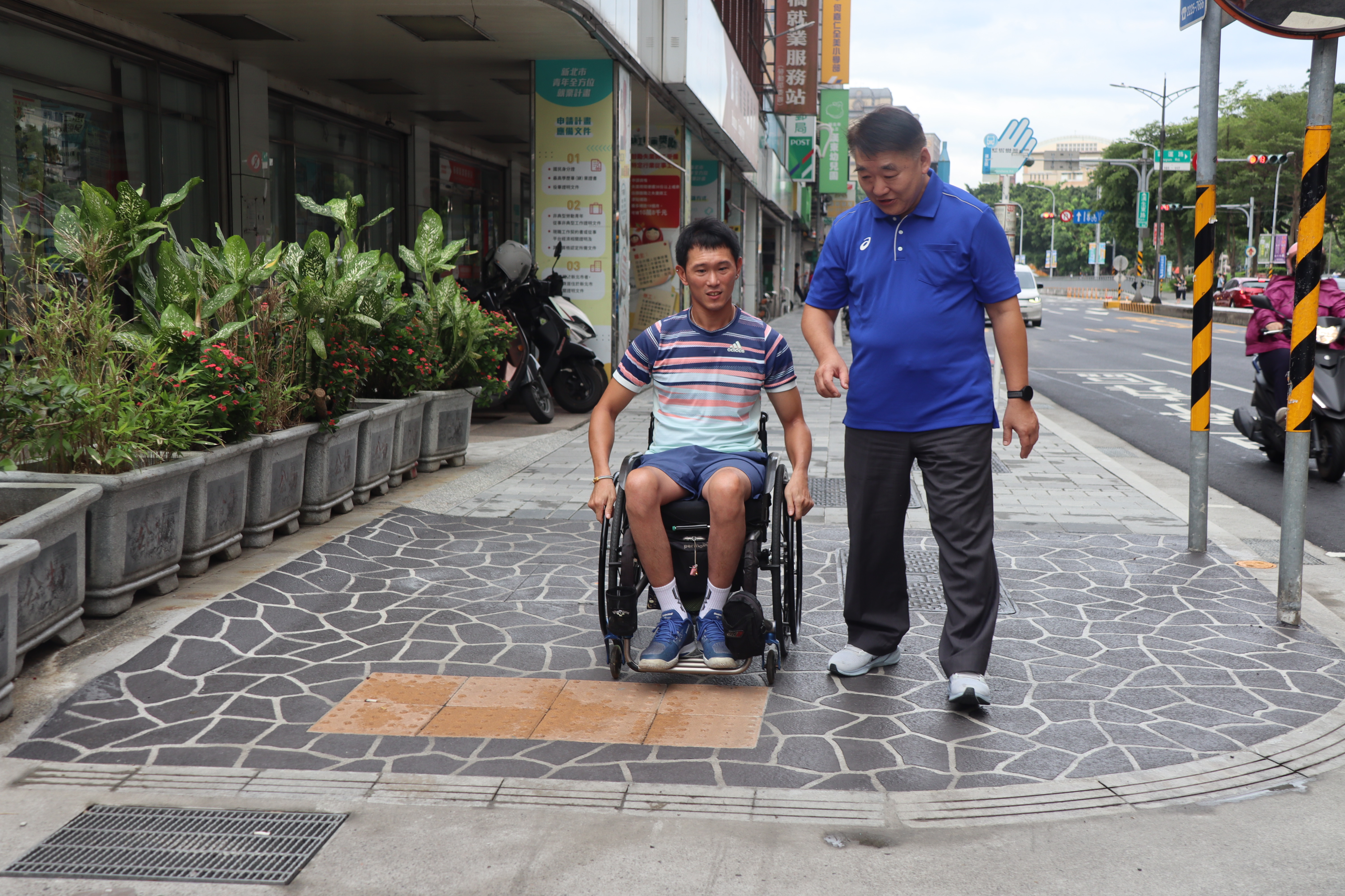 漢生東路人行道改善完成，工務局長馮兆麟(右)陪同輪椅網球選手唐兆漢(左)實地體驗，增設無障礙斜坡道銜接道路更平順，提升輪椅使用者通行便利性。