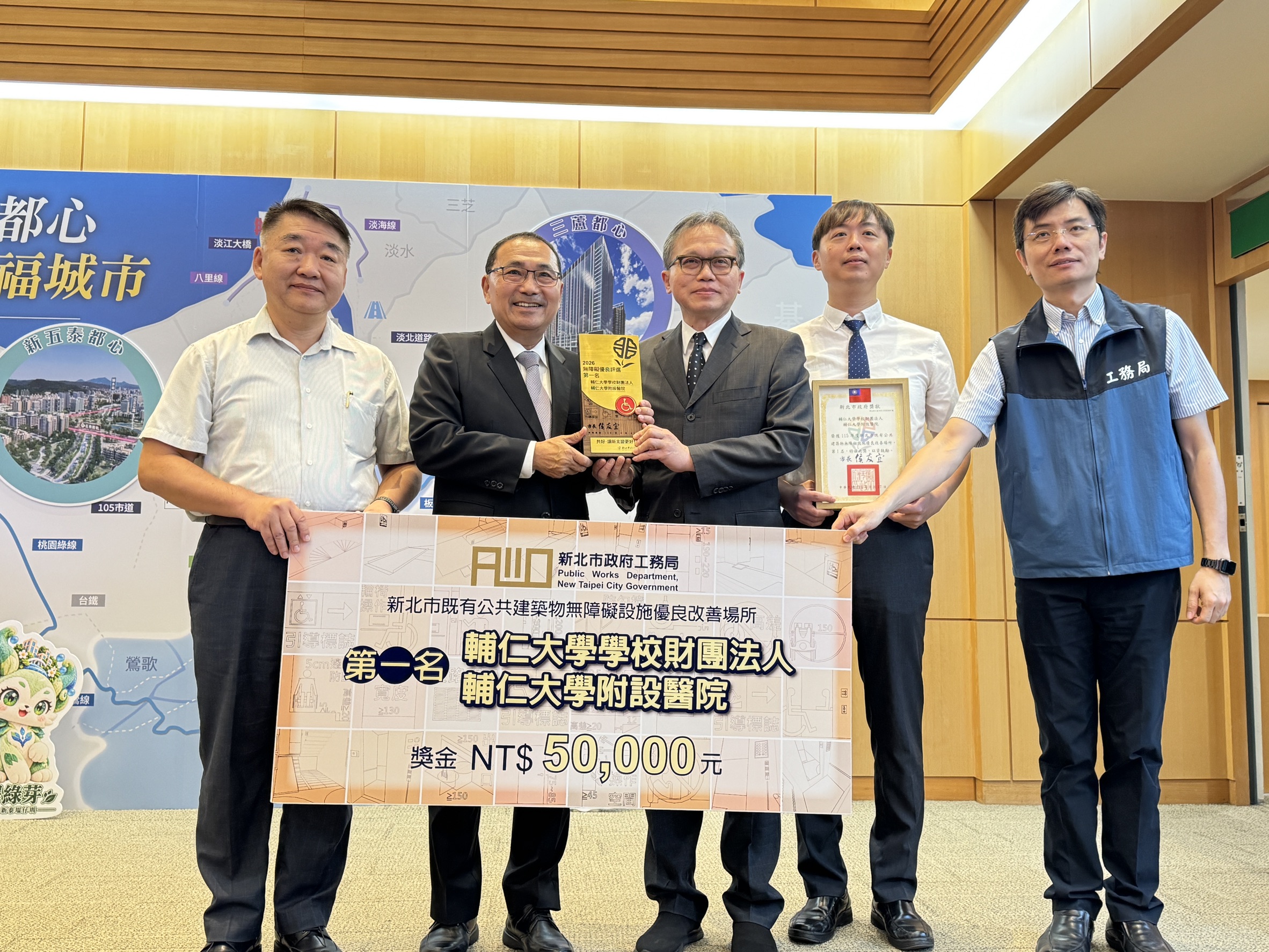 115年度新北市公共建築物無障礙優良場所出爐，輔大醫院評選為優等第一名，獲得獎金5萬元，侯友宜市長(左二)於市政會議中頒獎予以肯定，工務局長馮兆麟(左一)及使用科長陳敬勳(左五)等人合影留念。