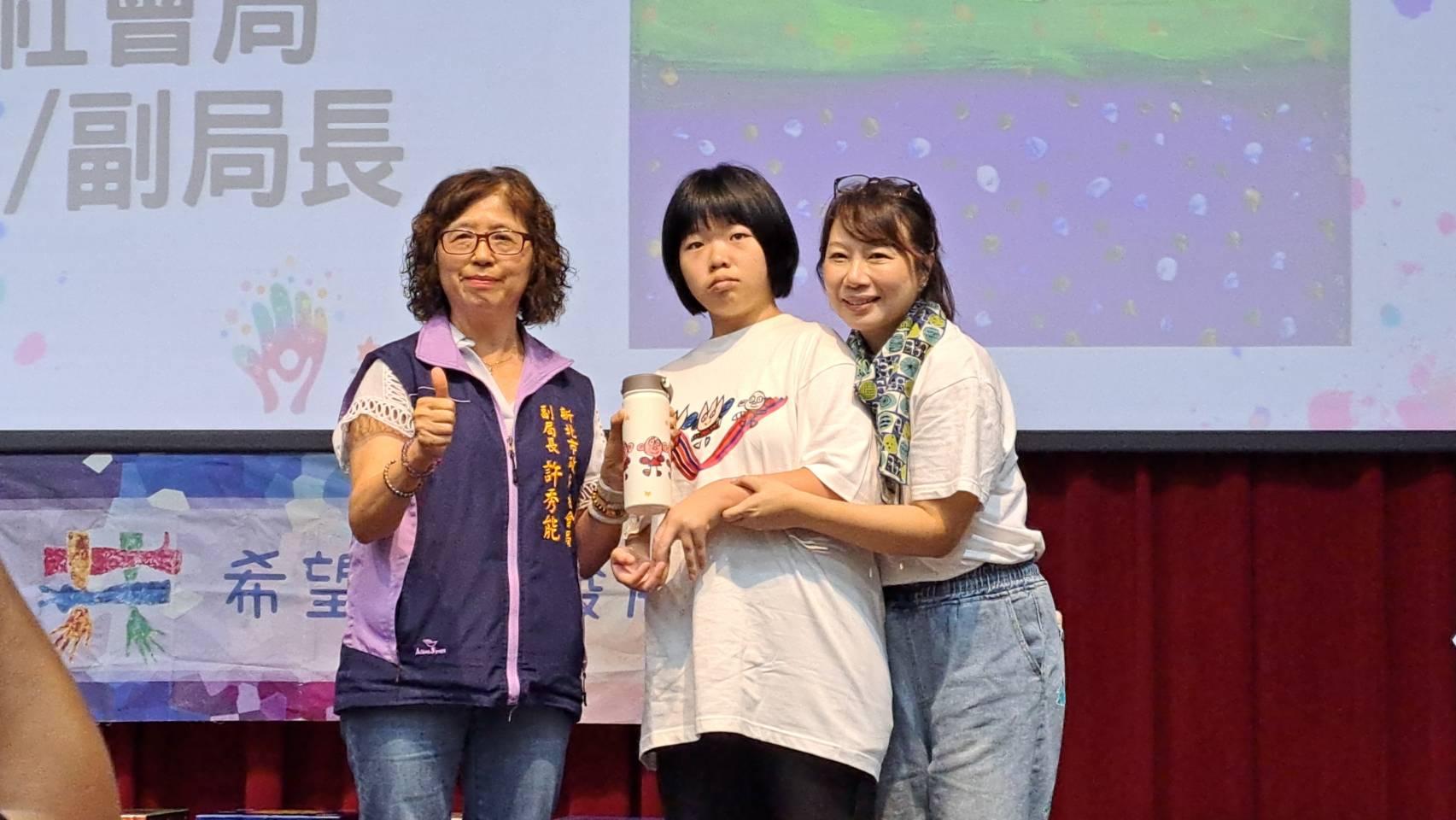  希望共好協會理事長呂蓮華（右）將學員LuLu（中）的畫作做成文創商品保溫瓷瓶