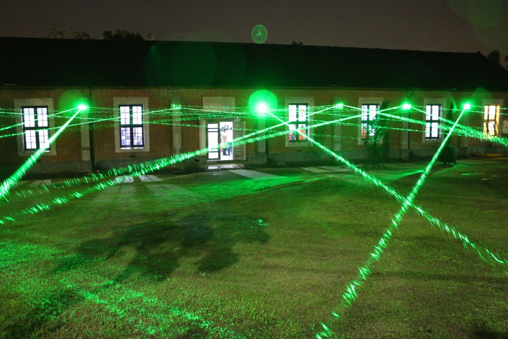 藝術家莊志維的《裝置微光計劃—海關碼頭》，以綠色的雷射光束在倉庫建築與戶外空間穿梭，在夜空中交織出一片光網，