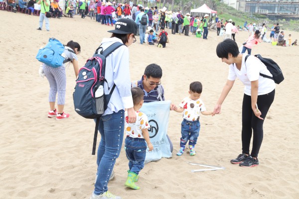 爸爸媽媽帶著小朋友共同參與淨灘活動，從小學習環境愛護的心