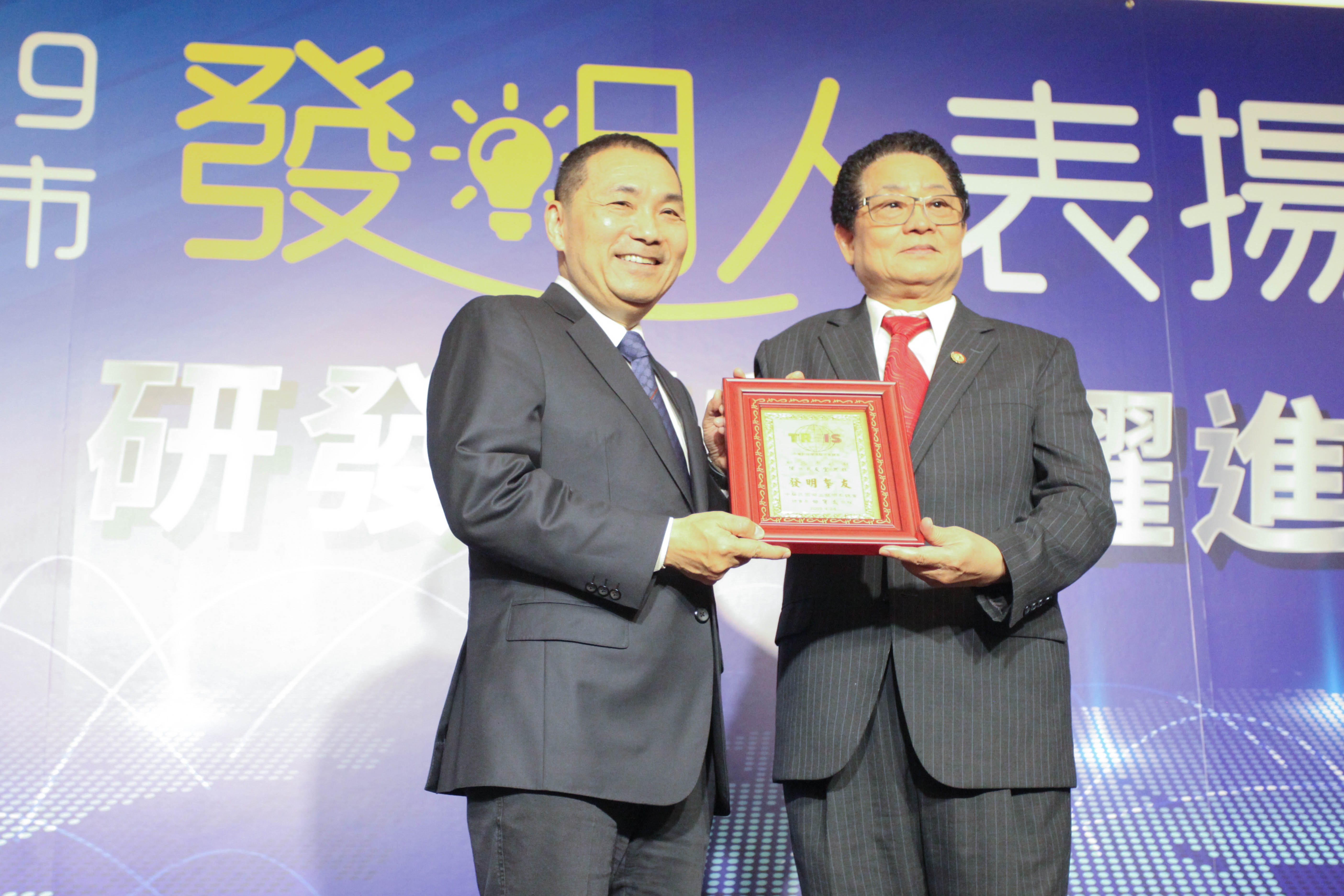 中華民國傑出發明家總會理事長田寶武(右)致紀念獎牌給新北市長侯友宜(左)