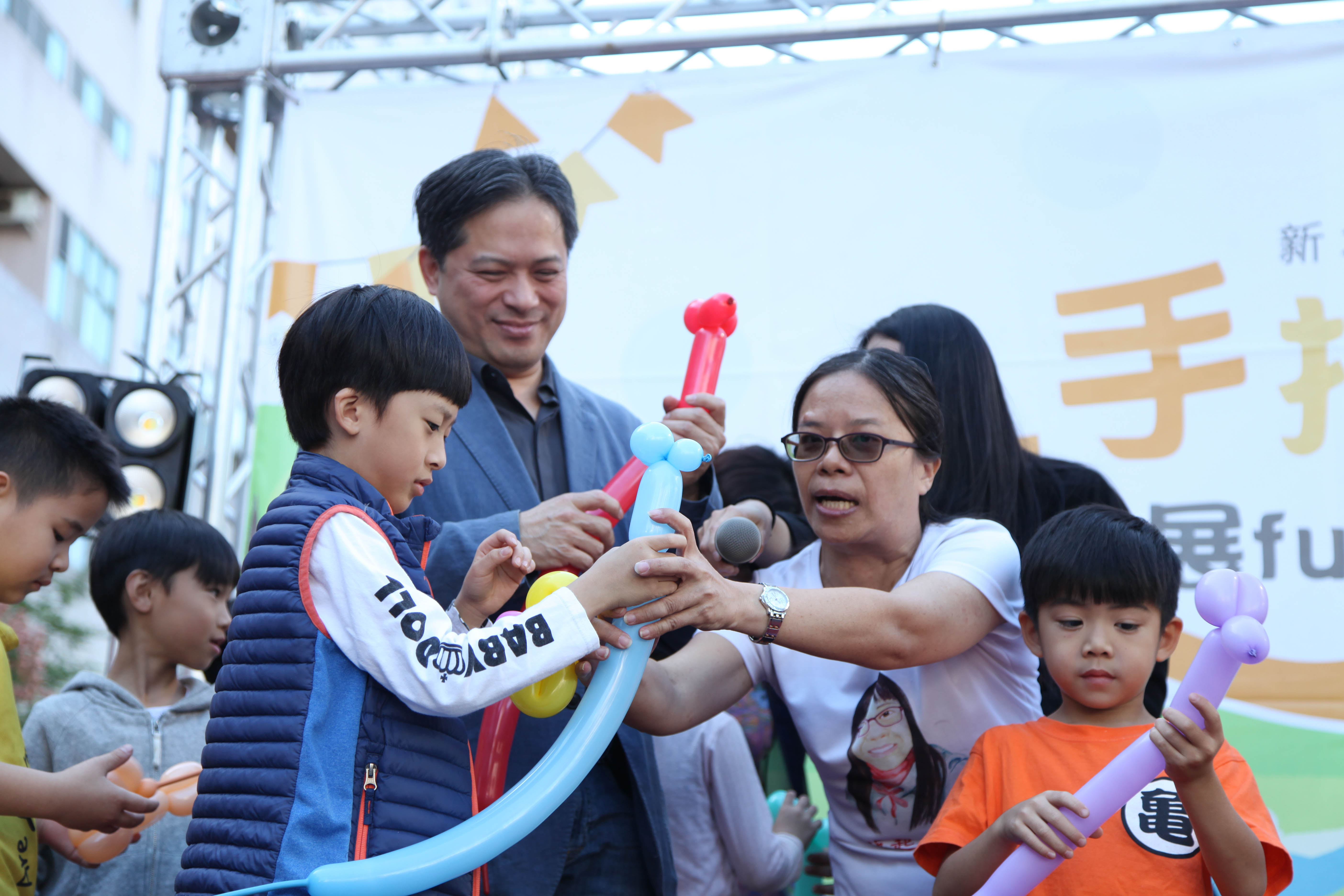 推臉部平權的社企團隊「藝起來串臉」在台上與吳明機副市長一起摺氣球，希望透過趣味親子互動體驗一起推廣社會企業。