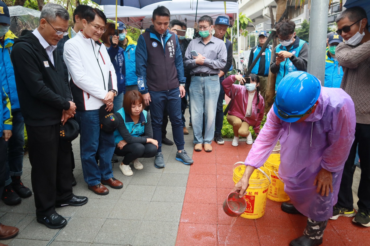 工程團隊於淡海輕軌人行道澆水展示透水鋪面功效。