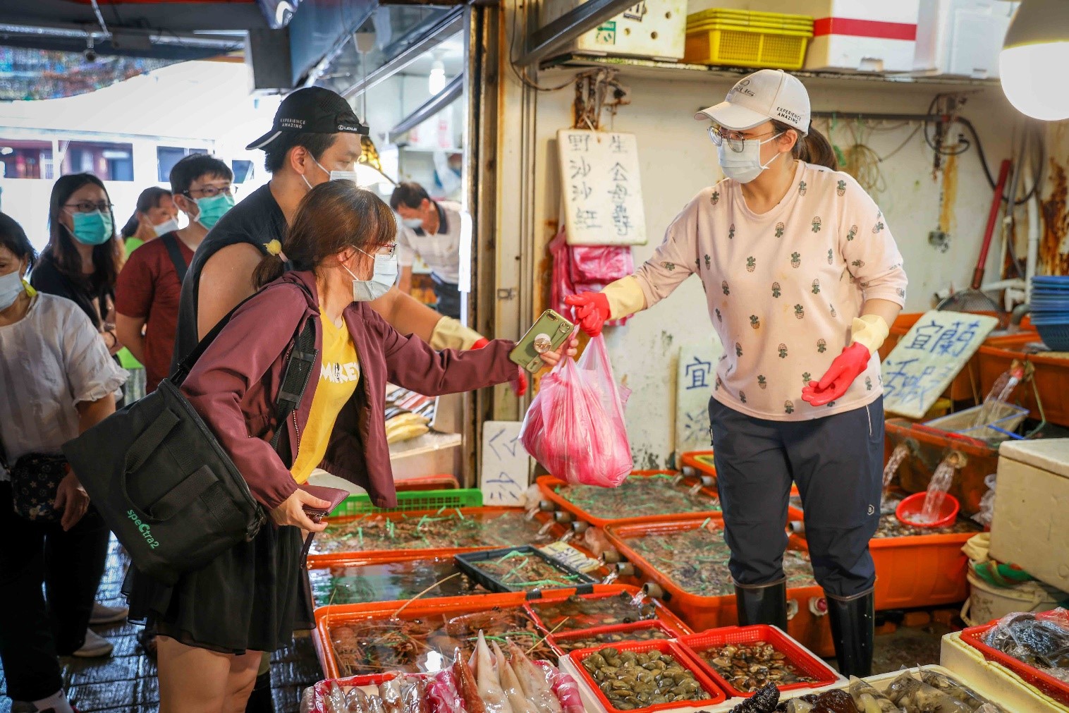龜吼漁夫市集商家將海產交給消費民眾，攤位上相當多萬里蟹等待挑選