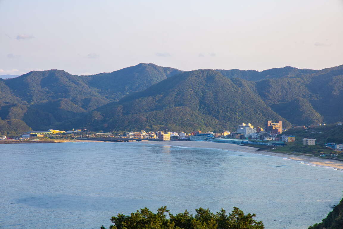 翡翠灣位於新北市萬里區,為北海岸知名的海灣景點。灣區弧形綿長,沿岸聚落與山景相映,構成海天一色的經典景觀。