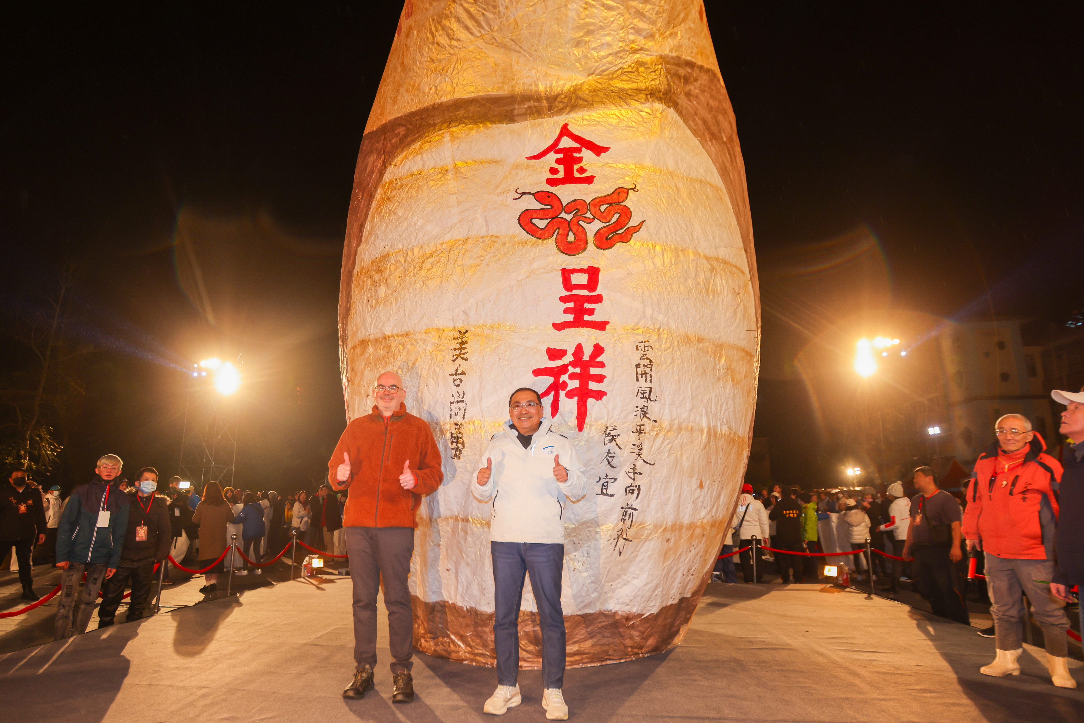侯友宜市長與AIT處長谷立言共同施放金蛇主燈，並在主燈上題字「雲開風浪平 溪手向前行」。